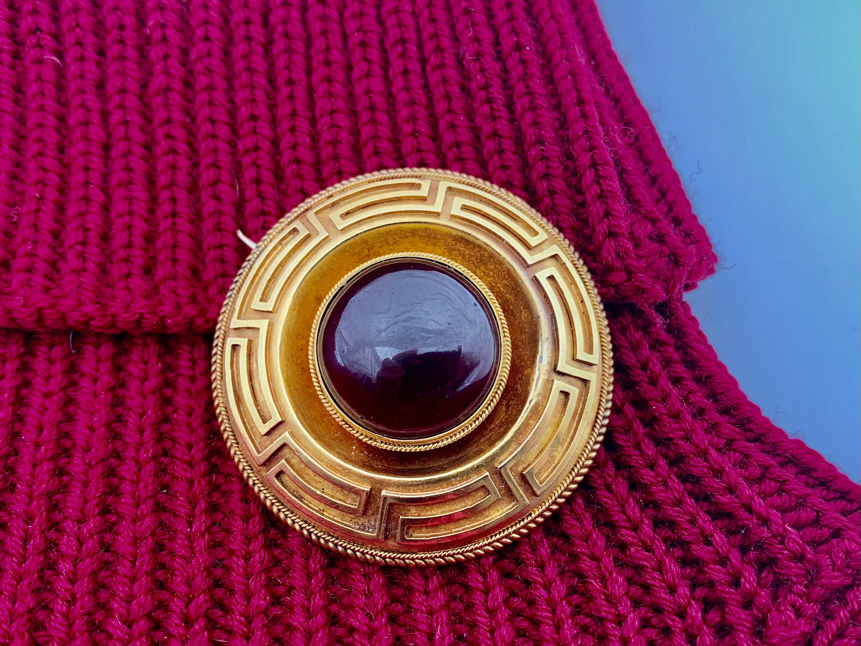 Superb quality antique Etruscan Revival gold and cabochon garnet Greek key motif disk brooch. Centered by a substantial 16mm round deep red cabochon garnet set in a rope twist frame within a dramatic concave textured gold circle surrounded by a bold