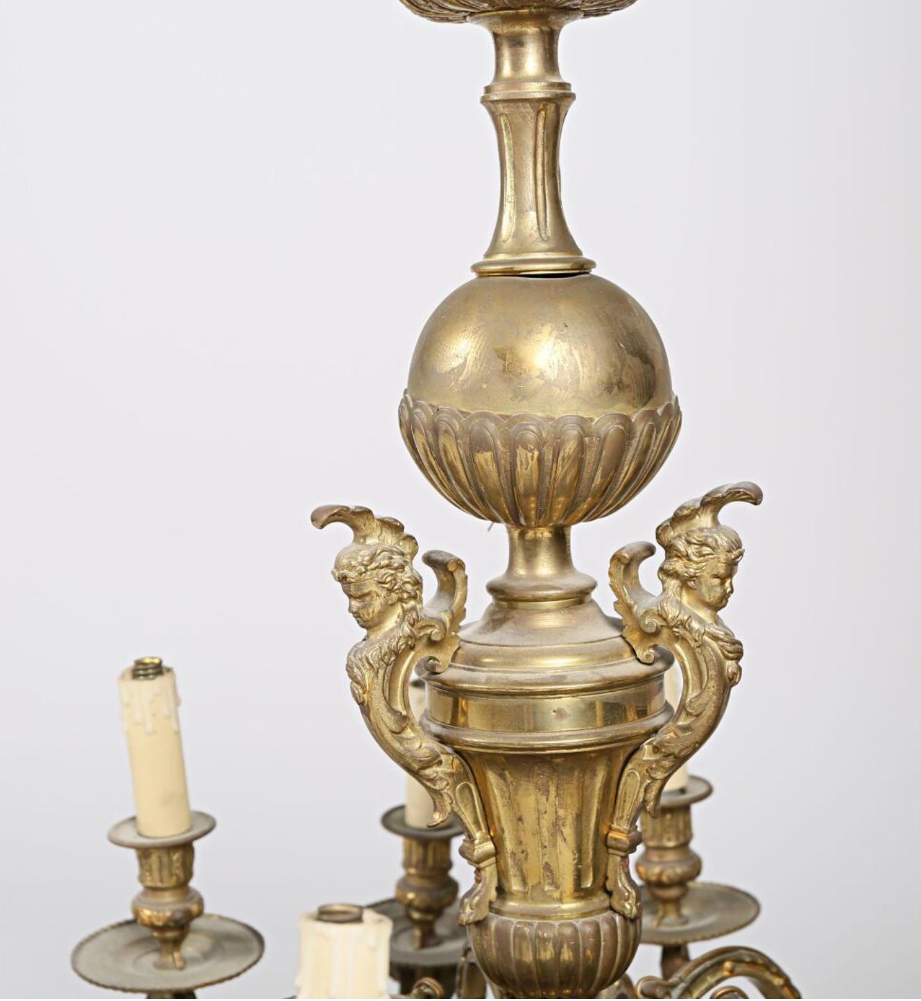 Bronze chandelier with twelve lights, there is sphere in the middle decorated with gadroons in its lower part underlined by three consoles decorated with busts and foliage it presents a basin with damping decorated with blooming acanthus leaves