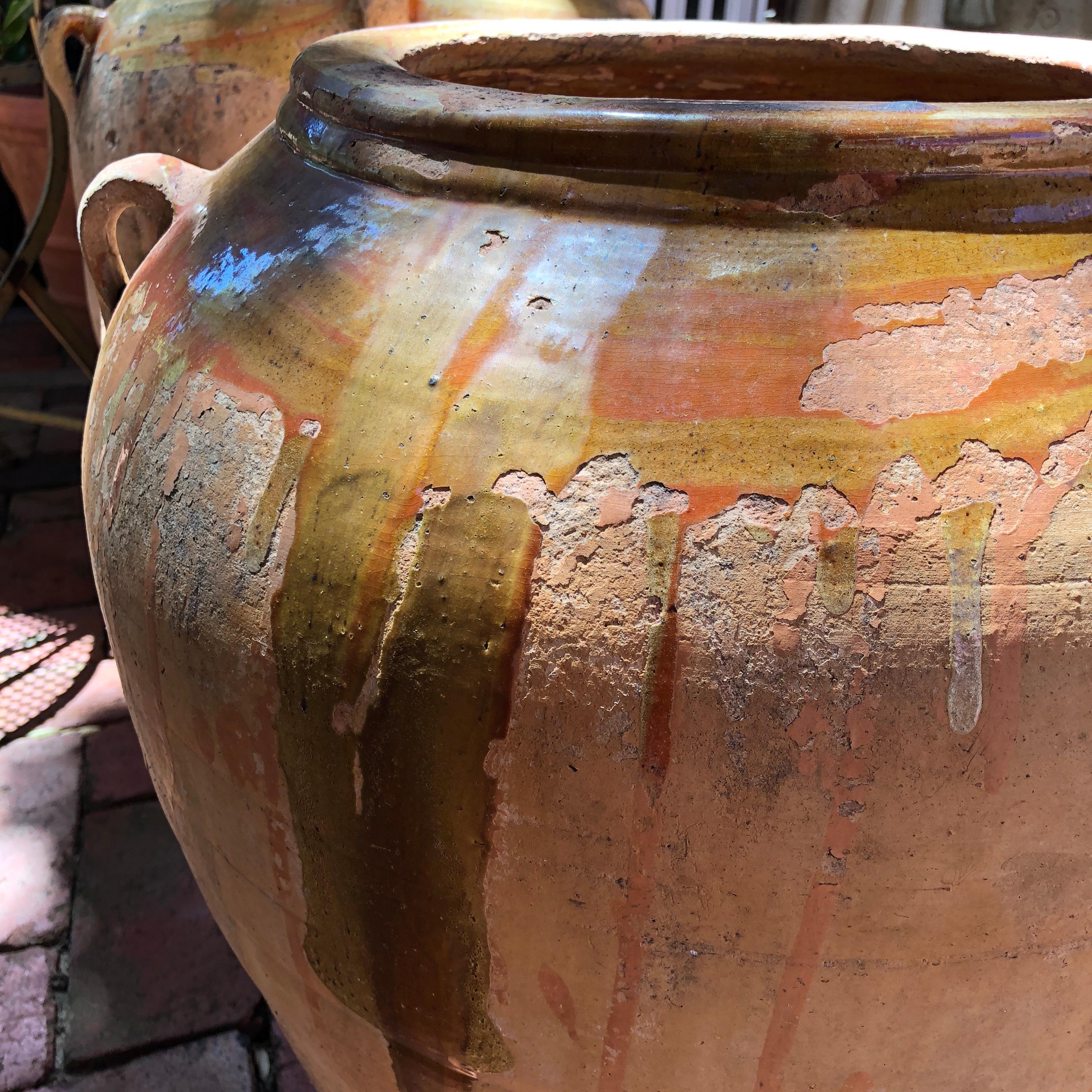 Featuring the signature South of France antique confit pot glaze, this rustic terracotta urn would make an exceptional jardinière or interior decorative item in any Province styled home. The patina of this 19th century urn ranges from a warm sienna