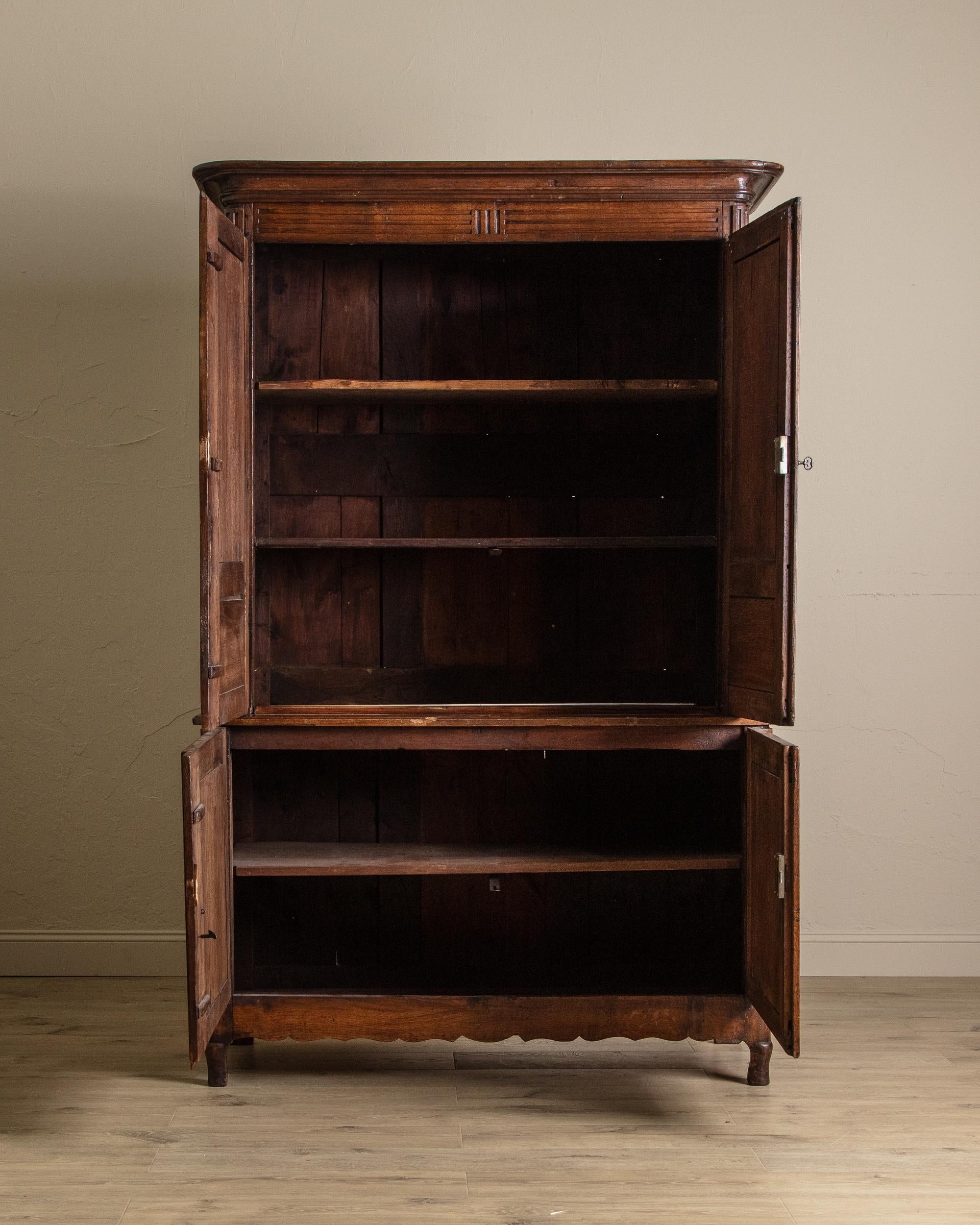 Cette armoire en chêne de style provincial français du XIXe siècle est une pièce majestueuse en deux parties qui allie rangement fonctionnel et élégance intemporelle. Fabriqué avec quatre portes à panneaux aveugles, il présente une patine