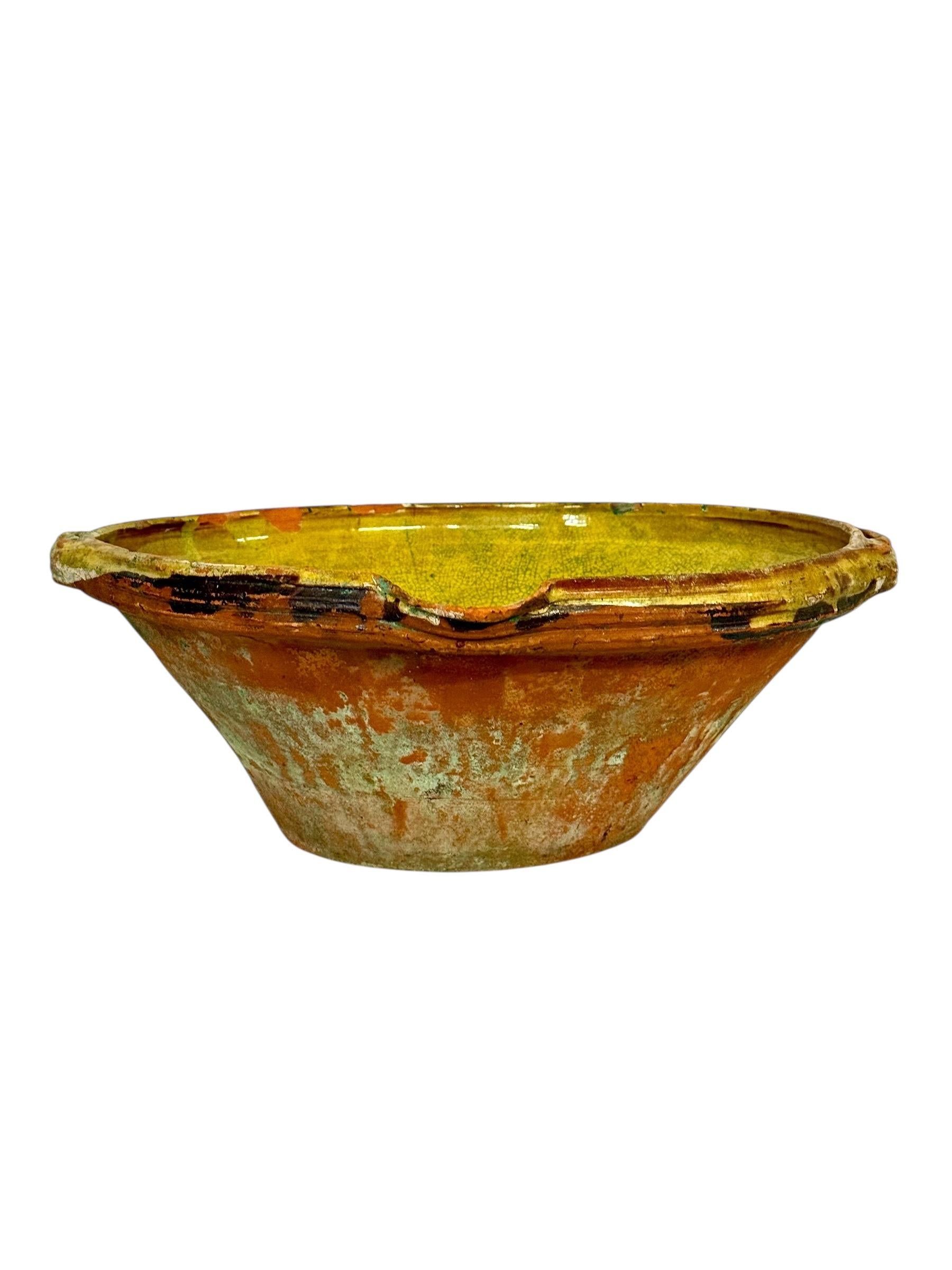 Questa straordinaria ciotola in terracotta francese del XIX secolo è un bellissimo esempio di ceramica utilitaristica, impreziosita dal tempo, dalla patina e dal fascino autentico. Realizzata a mano nel sud della Francia, probabilmente nelle regioni
