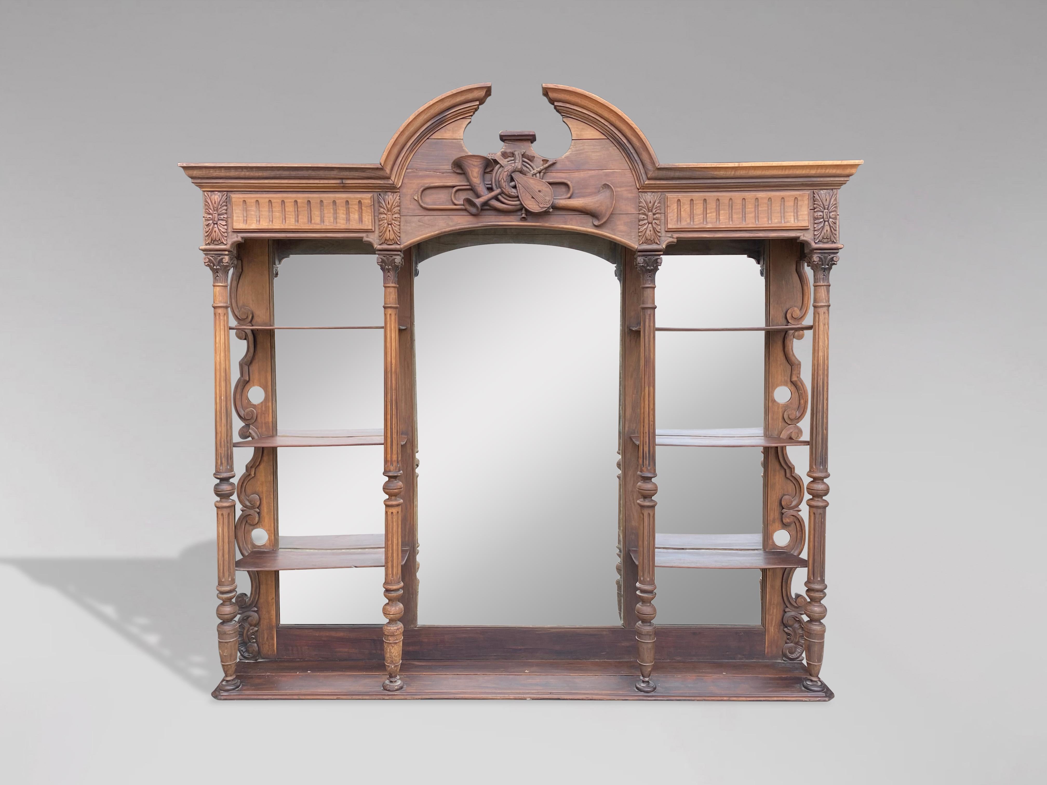 A very decorative large 19th century French carved and ornate walnut back bar shelving unit or étagère with a moulded swan neck pediment above a carved hunting sculpture, three large mirrors, four attractive carved, reeded turned walnut columns