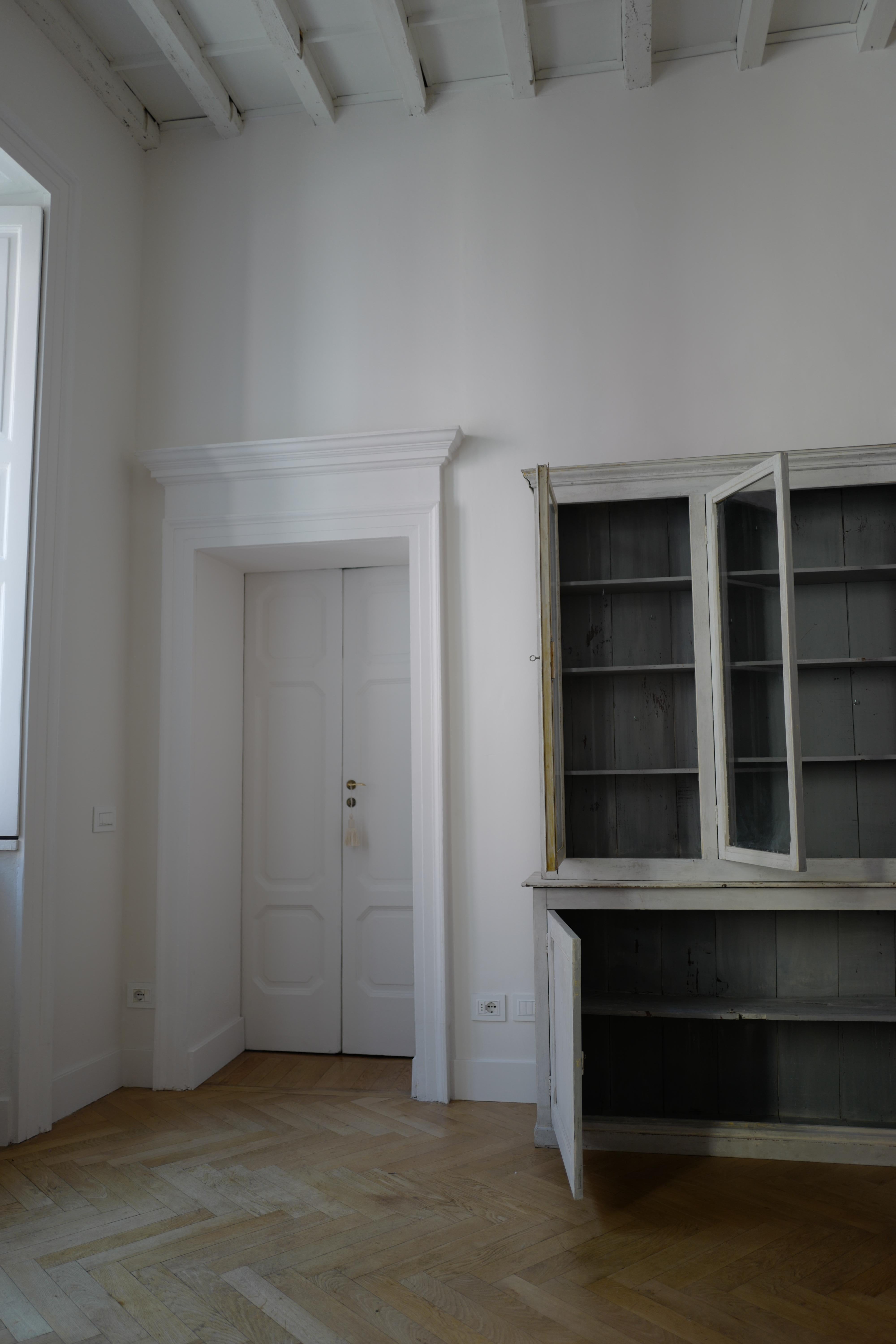 This French Provincial large display case is a statement in any space. Off white/grey painted oak exterior and a light blue/grey painted interior. Featuring original wavy glass in all but one door. The far left door's original glass broke during
