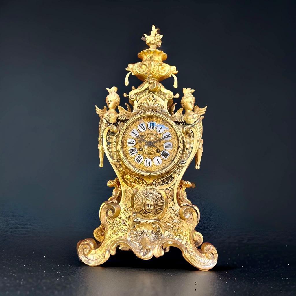 Wir präsentieren Ihnen diese große und außergewöhnliche Uhr aus vergoldeter Bronze, die 61 cm hoch und 31 cm breit ist. Sie ist mit vergoldeten Frauenbüsten aus Bronze auf beiden Seiten des Zifferblatts verziert, die den opulenten Stil der Ära