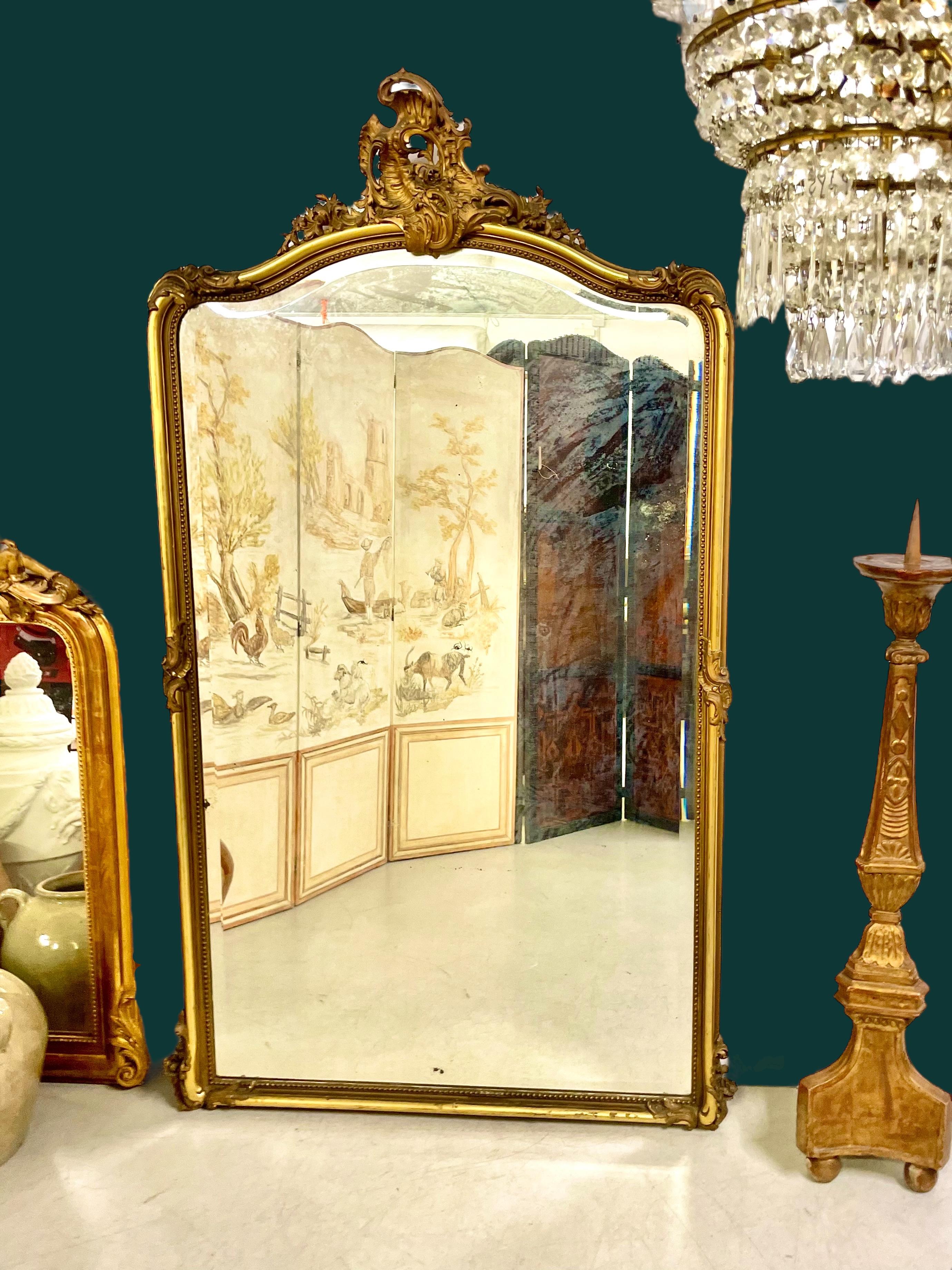 Dieser prächtige französische Spiegel ist ein hervorragendes Beispiel für die Handwerkskunst des 19. Jahrhunderts und vereint Grandeur, Eleganz und feine Ornamente. Das aus Holz und Stuck gefertigte und vollständig vergoldete Stück fängt mit seinen