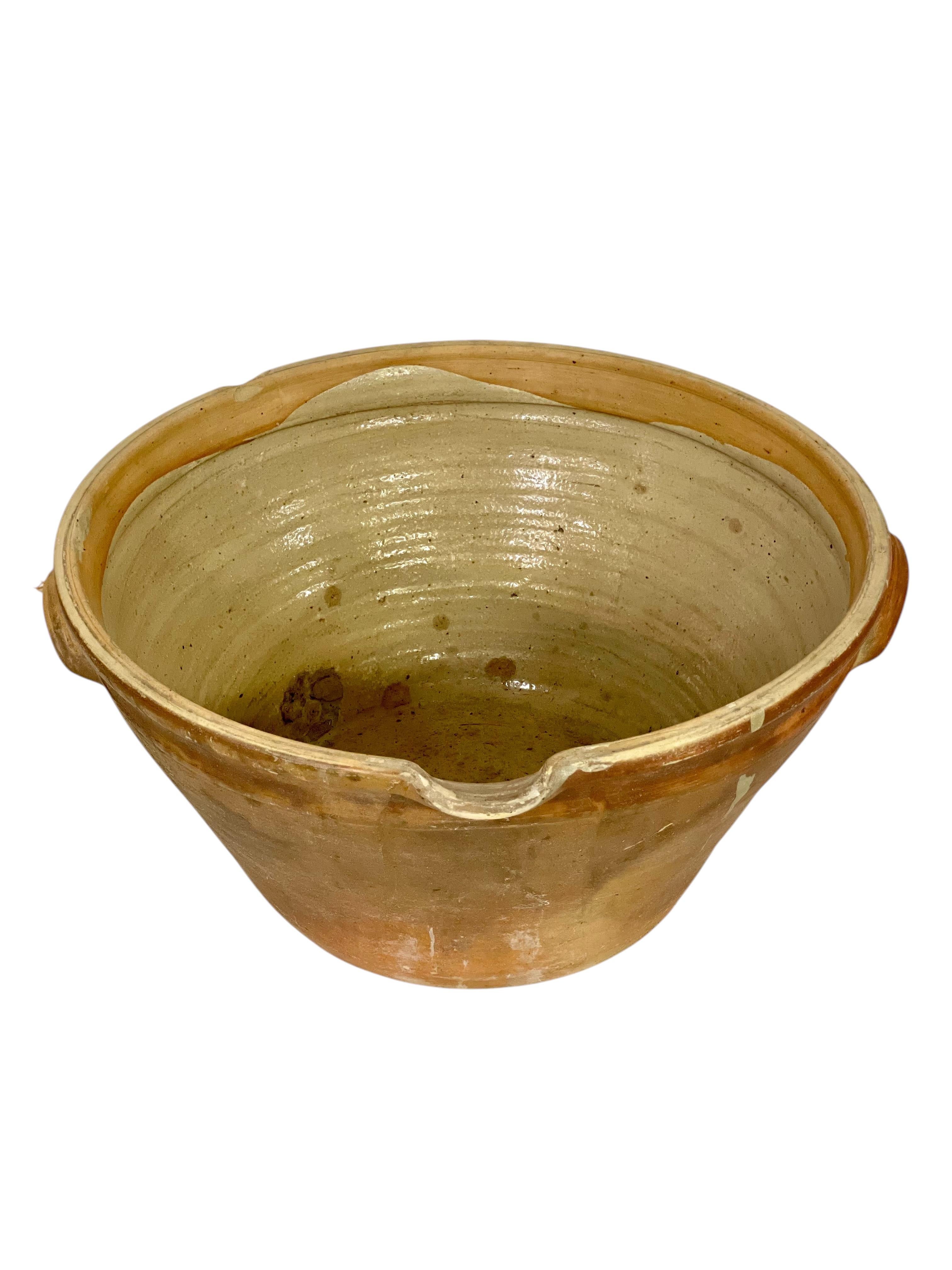 Este excepcional cuenco antiguo de cerámica francesa es un impresionante ejemplo de artesanía rústica y diseño atemporal. Con unas impresionantes medidas de 53 cm de diámetro y 25 cm de altura, este gran recipiente es tan práctico como bello.