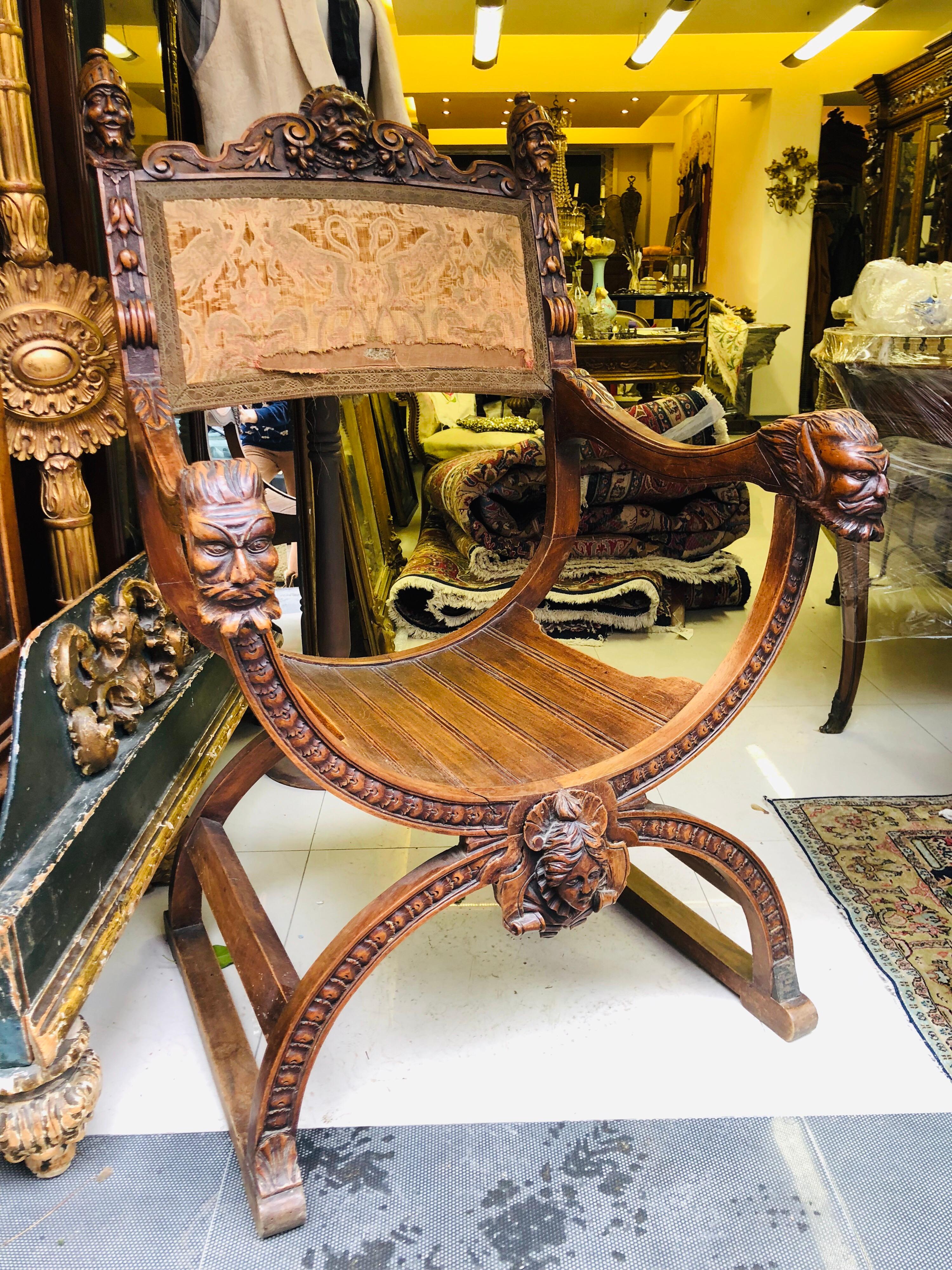 Large Savonarola chair in walnut carved with heads of characters, helmeted warriors, fauns, foliage and acanthus. Henry II style, late 19th century. 
Measures: Height 112 cm, width 62 cm, depth 58 cm.