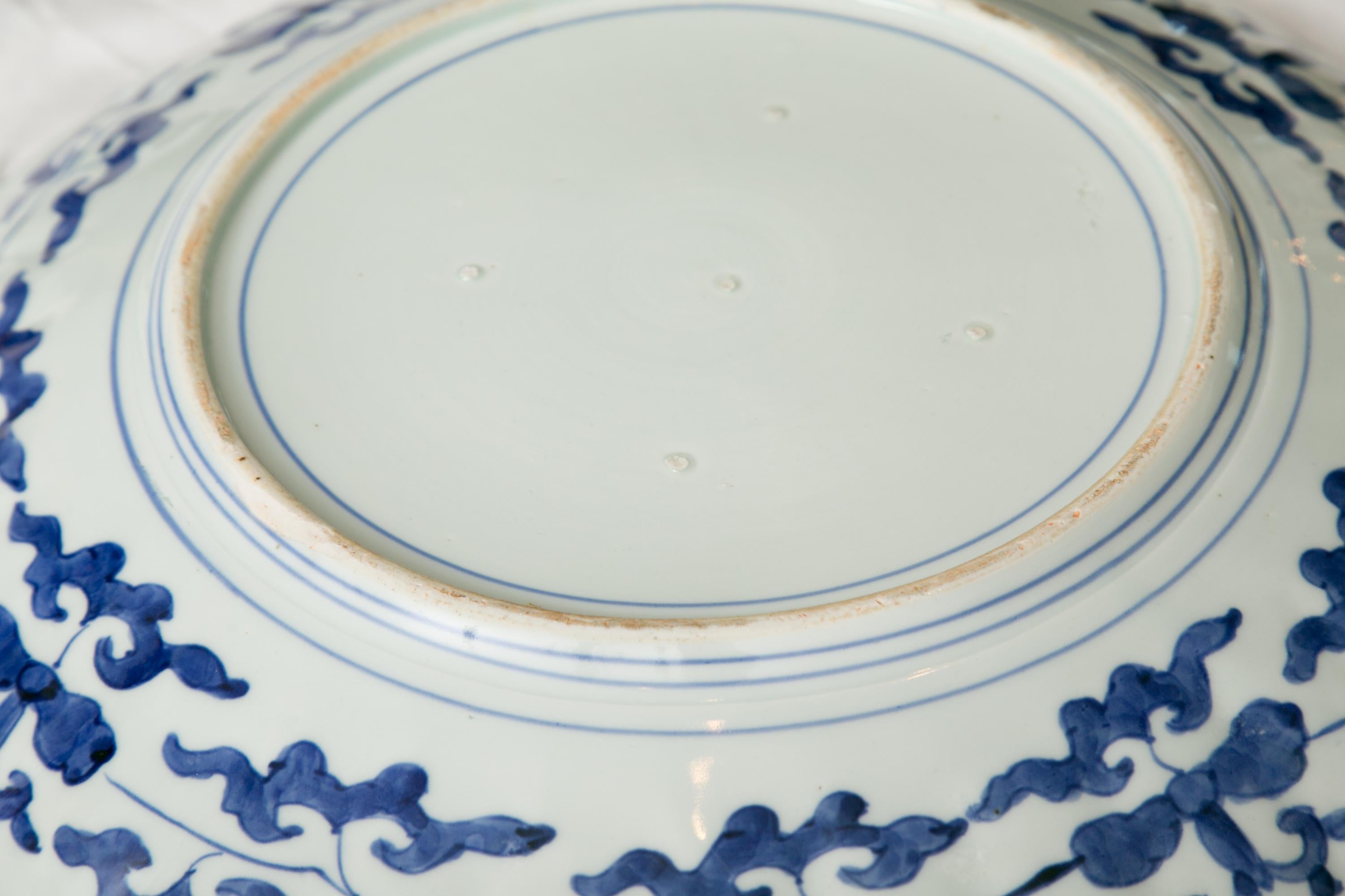 This is a classic Imari charger with scalloped edge and exhibiting bold colors of cobalt blue and bittersweet, with underglazed blue markings around perimeter of bottom, circa late 19th century.