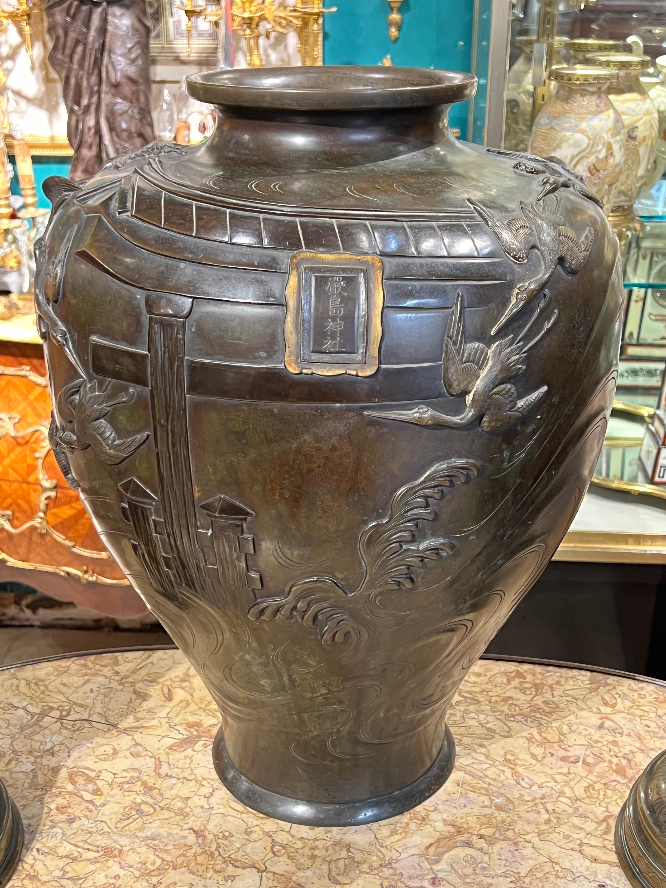 Large antique (19th century) Japanese patinated bronze centerpiece vase with  fine reliefs depicting cranes in flight above the sea with waves and temple gate representing the Itsukushima Shrine.  Signed 嚴島神社  for Itsukushima Shrine.
