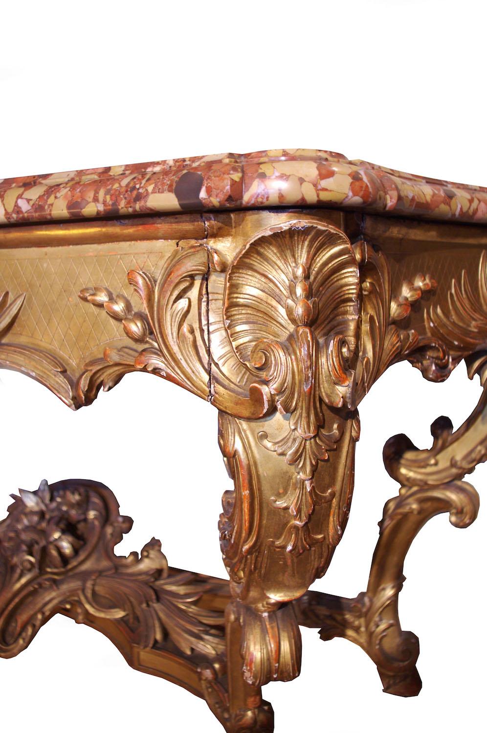Large decorative carved and giltwood Louis XV style console, standing on four curved legs ending with hooves and linked by an X-shaped stretcher decorated in the middle with a large trophy extended by acanthus leaves. The chantourné belt has an