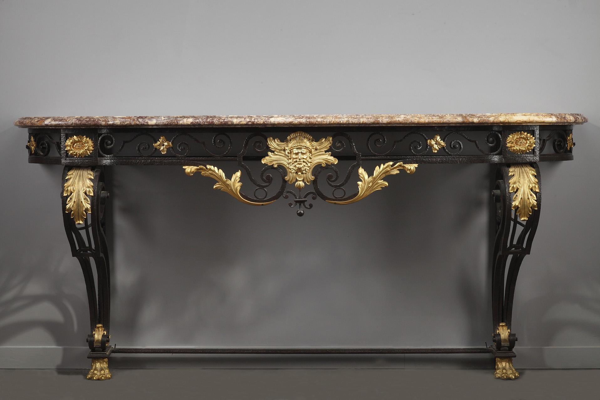 Fashioned in the Louis XV style, this large French console table is crafted of hammered, black and gilt lacquered wrought iron. Crafted with meticulous attention to detail, the openwork belt is decorated with scrolls, flowers and bearded mask