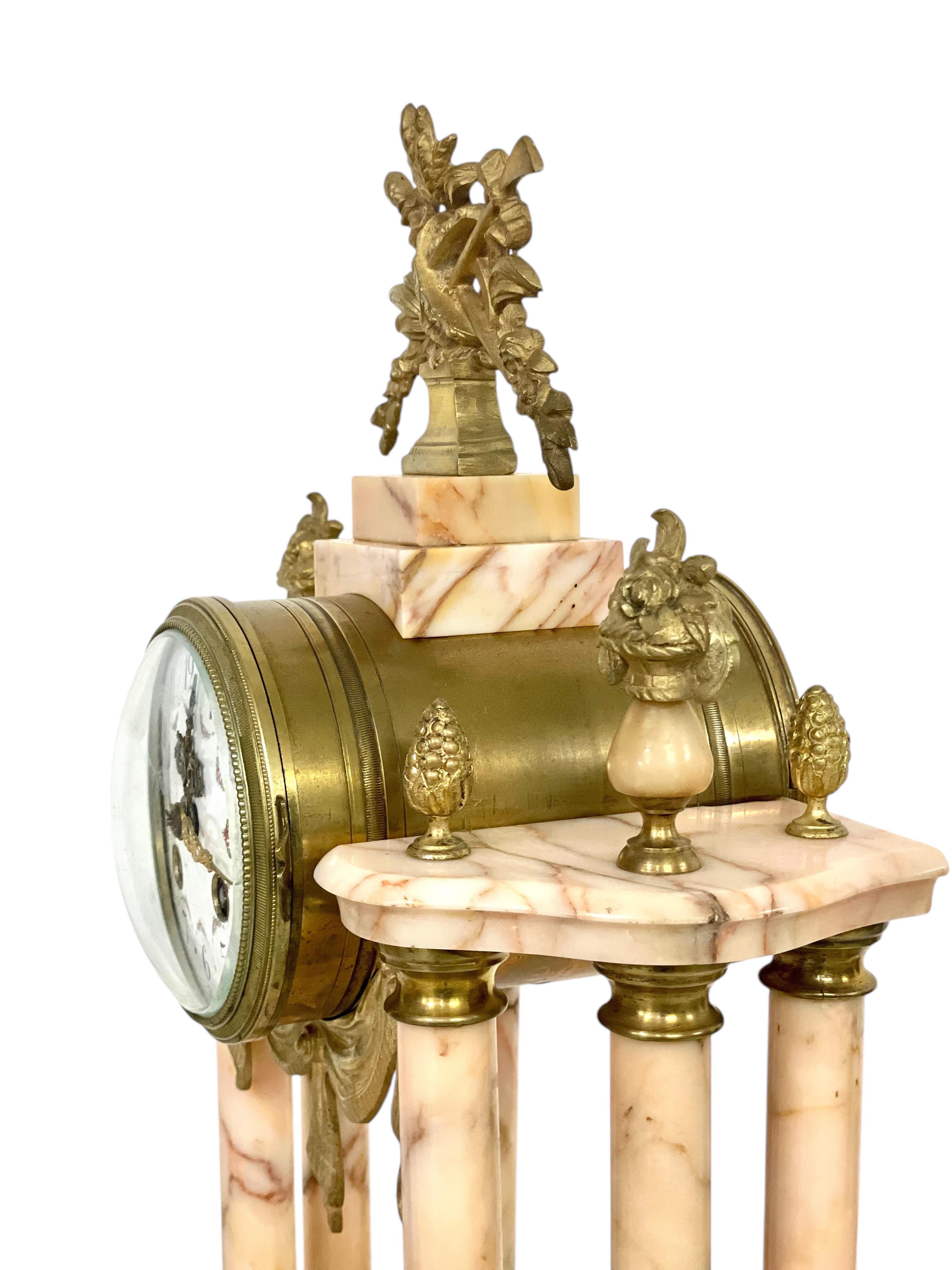 Elegant antique clock garniture set, crafted from striking pink-veined marble and adorned with ornate gilded bronze details. This exquisite 19th-century set features a central clock flanked by two matching urn-shaped garnitures, each standing on a
