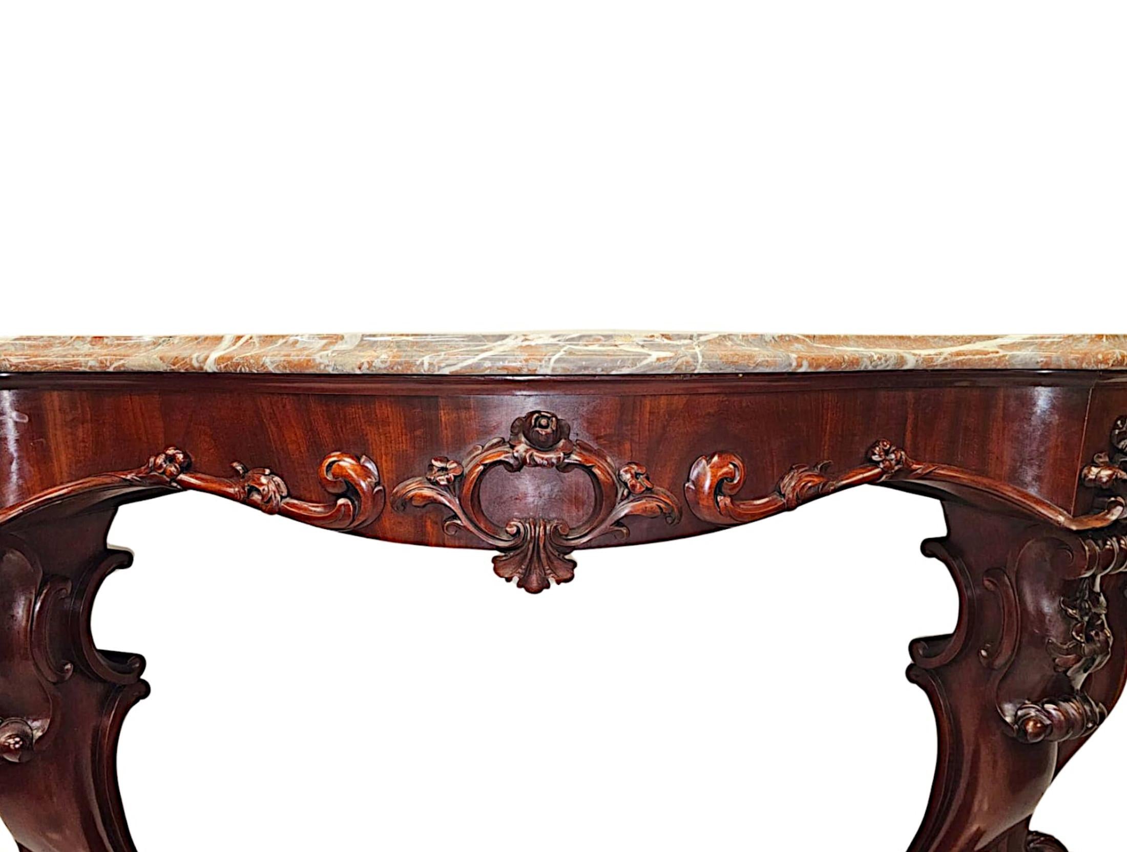 A stunning 19th Century well figured mahogany marble top console table of large proportions, finely hand carved with beautifully rich patination and grain.  This exceptional piece features a striking moulded, serpentine fronted Rosso Levante marble