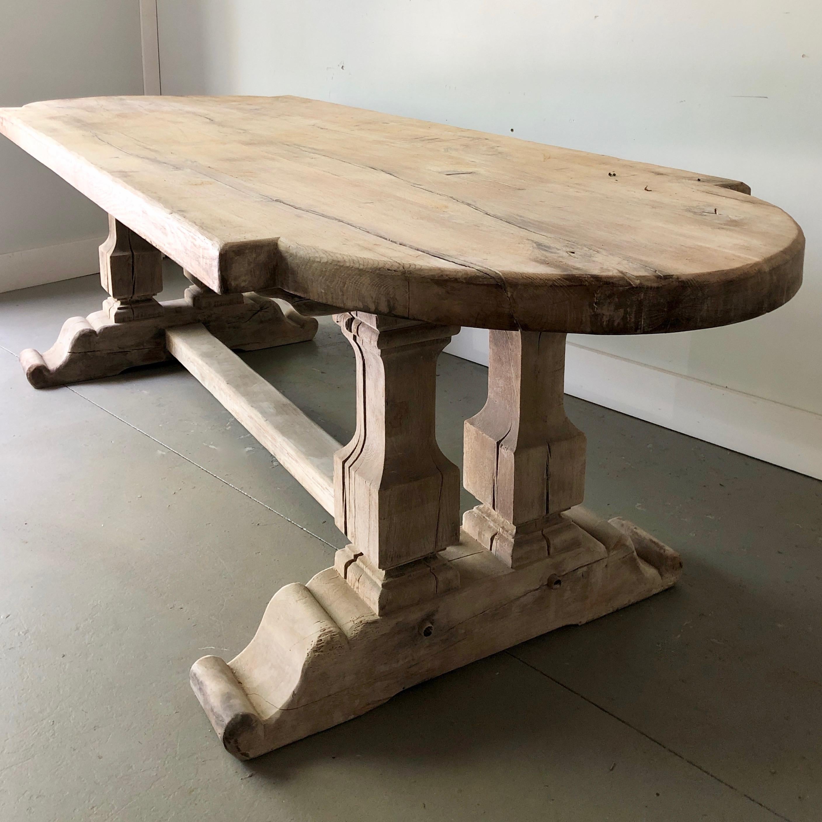 19th century French Monastery table with very thick and heavy shaped oak top is supported by a pair of trestle legs and the beam of the H-shaped stretcher.