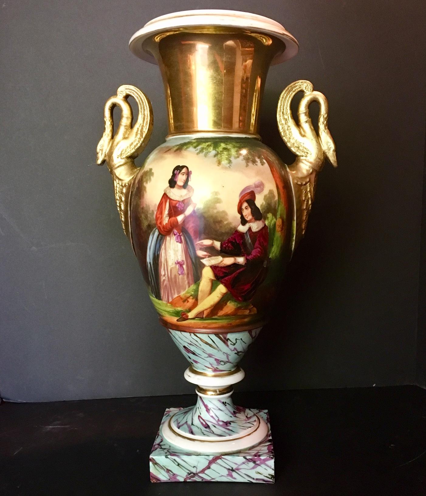 This beautiful early Old Paris vase dates from the early 19th century. In the front It features a finely hand painted romantic couple. The back pictures a lovely landscape. The vase is flanked by a pair of elegant swan handles. Some illegible relief