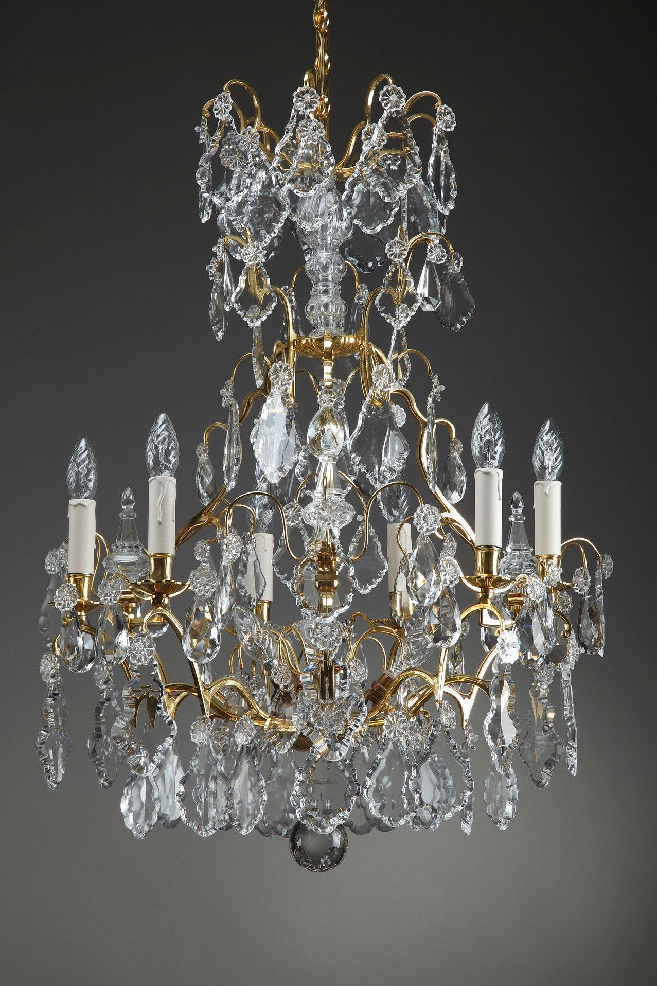 This late 19th century crystal chandeliers of large size and opulent decoration is an exquisite antique collectible to behold. It boasts 9 ormolu branches, richly decorated with oversized drops, flowers and daggers in crystal. Each chandelier has a