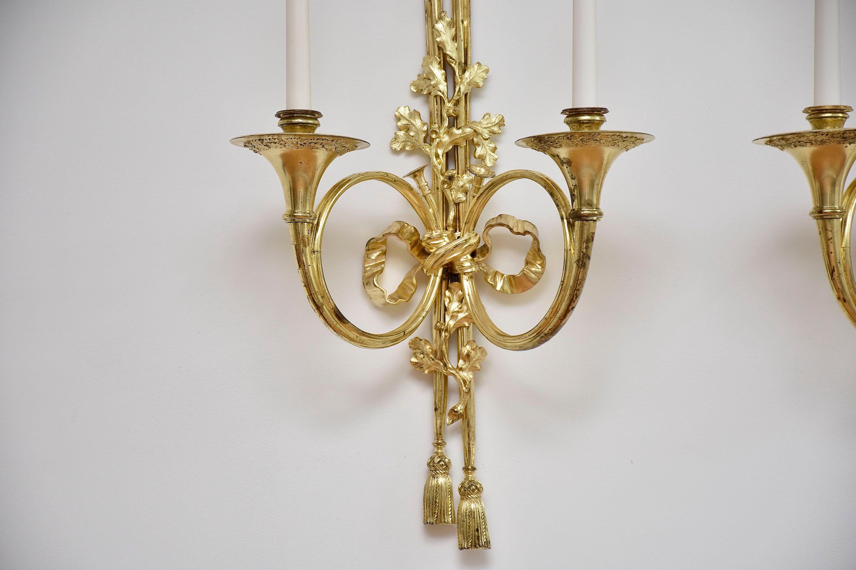 Ein schönes und sehr beeindruckendes Paar französischer zweiflammiger Wandapplikationen im Stil Louis XVI.
Jeweils mit Rückwand in Form von mit Quasten versehenen Draperien, die mit verschlungenen Eichenzweigen, einem Schleifenband und zwei Hörnern
