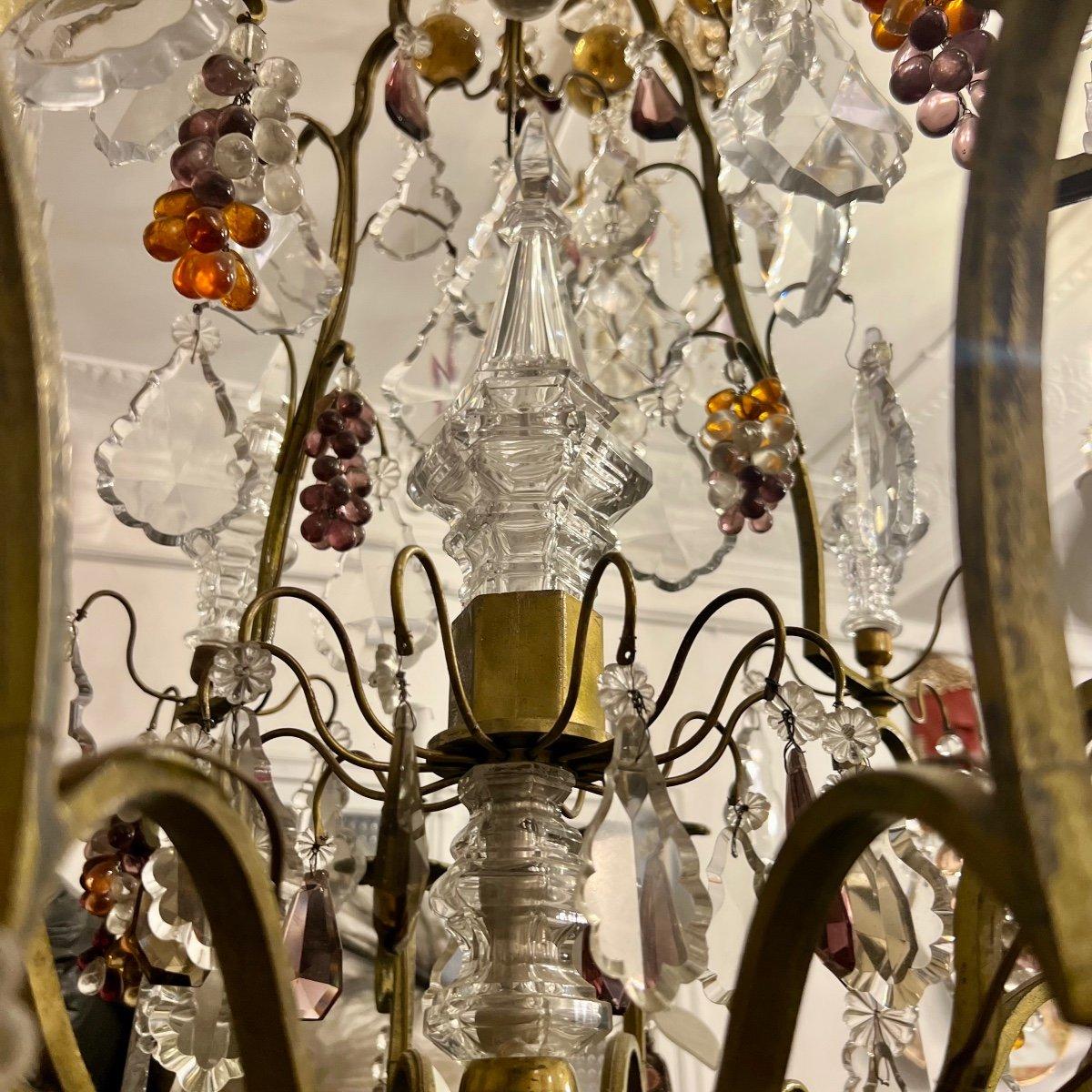 Questo eccezionale pezzo del XIX secolo è un monumentale lampadario Saint Louis, interamente realizzato in bronzo e sontuosamente ornato da un decoro opulento: grappoli d'uva, pere e foglie di cristallo finemente intagliate, il tutto arricchito da