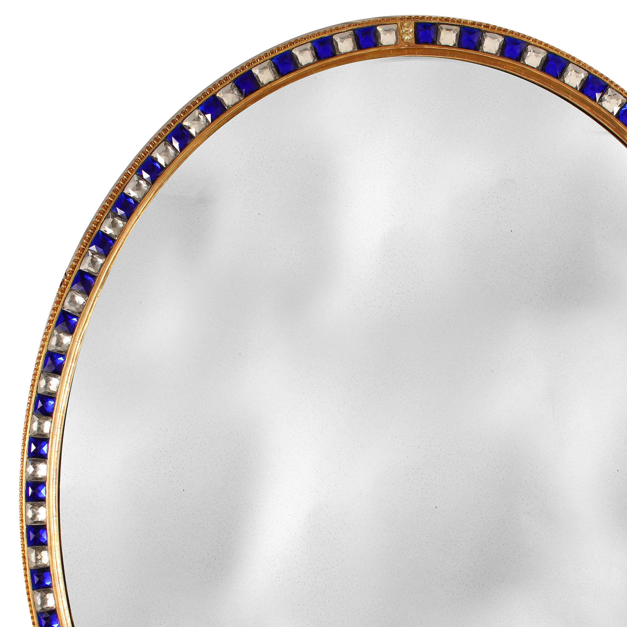 A fine 19th century oval mirror of large scale with giltwood border inset with clear and blue glass cabochons. 
England, circa 1880

Size: 54 inches (137cm) high, 43.5 inches (110.5cm) wide.