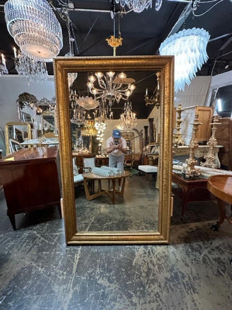 Handsome 19th century large scale French transitional gold leaf mirror. Featuring a scrolling pattern on the base and a braided outside border. Great for a large space. Lovely!!