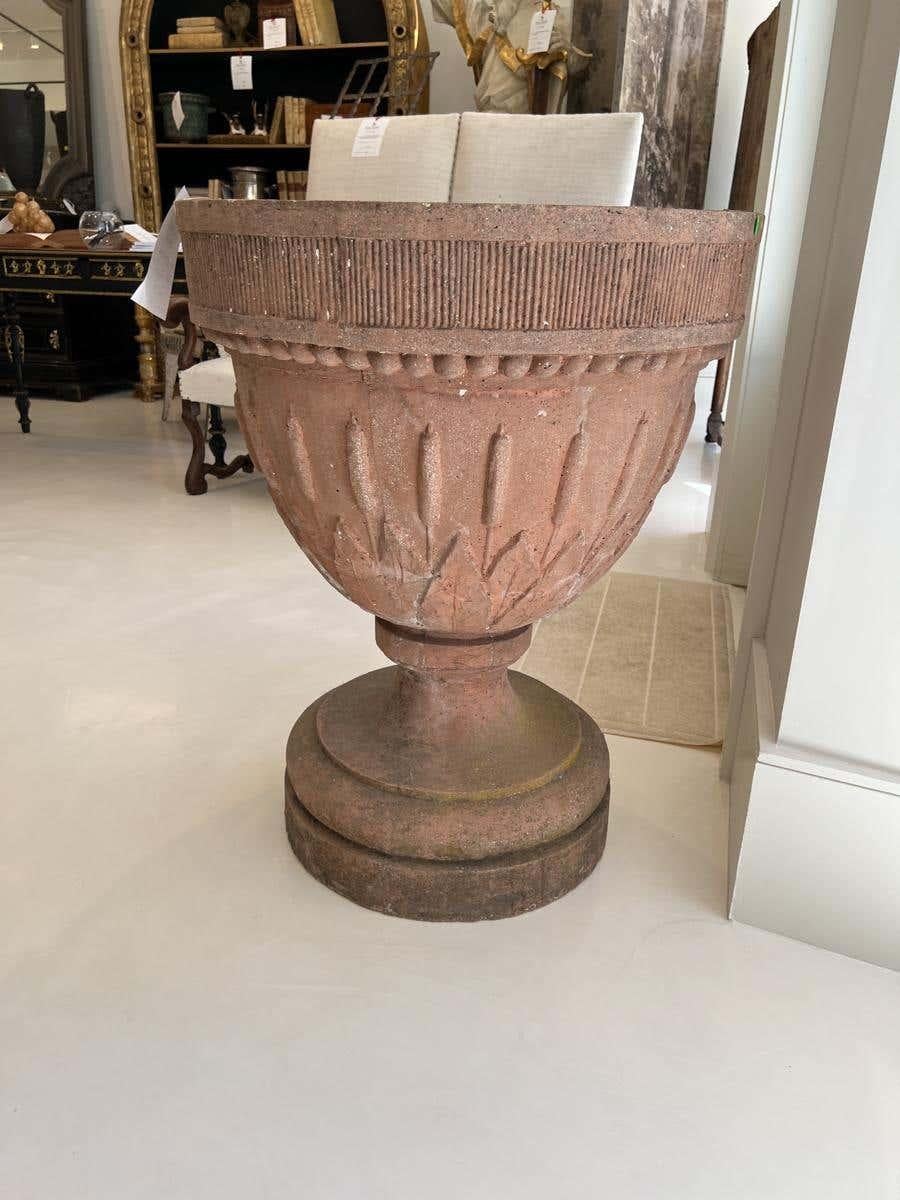 Large terra cotta planter with cattail motif encircling the large bowl.
