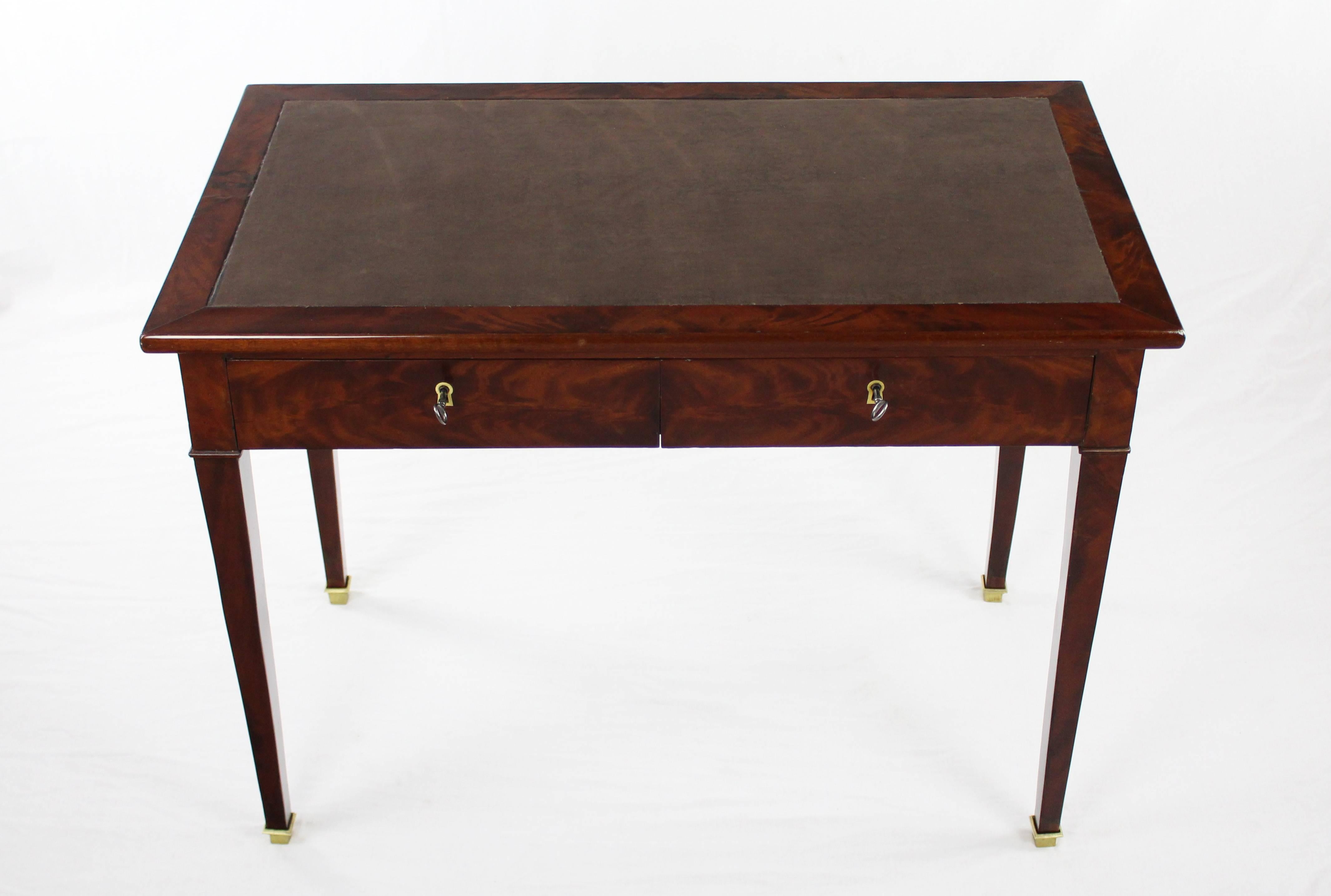 An elegant and graceful straight-lined desk from the late Biedermeier period, worked circa 1840-1850 in mahogany veneered on oak. The table has a leather inlay on the slightly overhanging top, as well as two separately lockable drawers under the