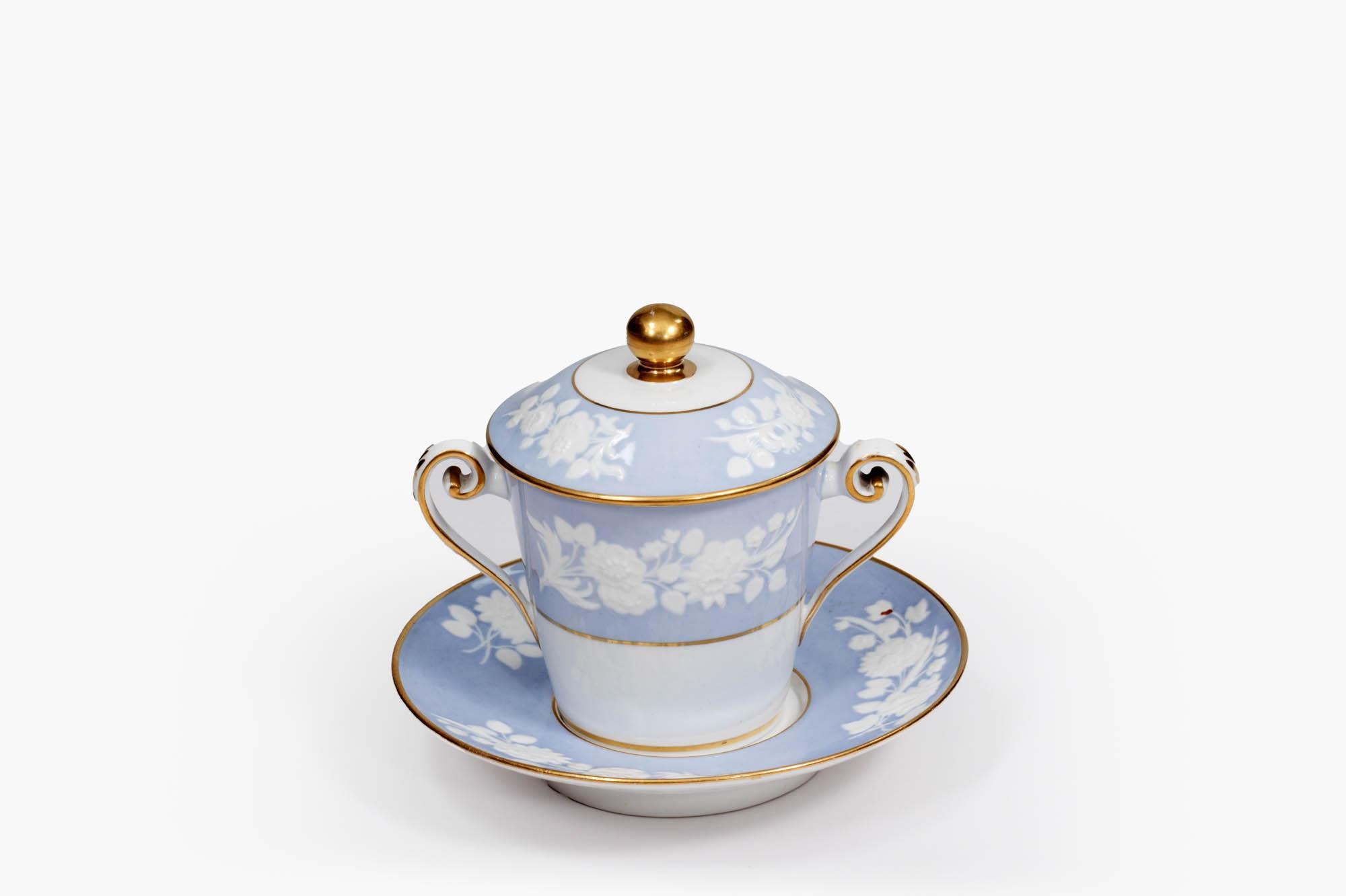 19th century late Georgian blue spode hot chocolate cup with cover and saucer, decorated with gilt highlights, and embossed white floral motif on a pale blue background. circa 1800.