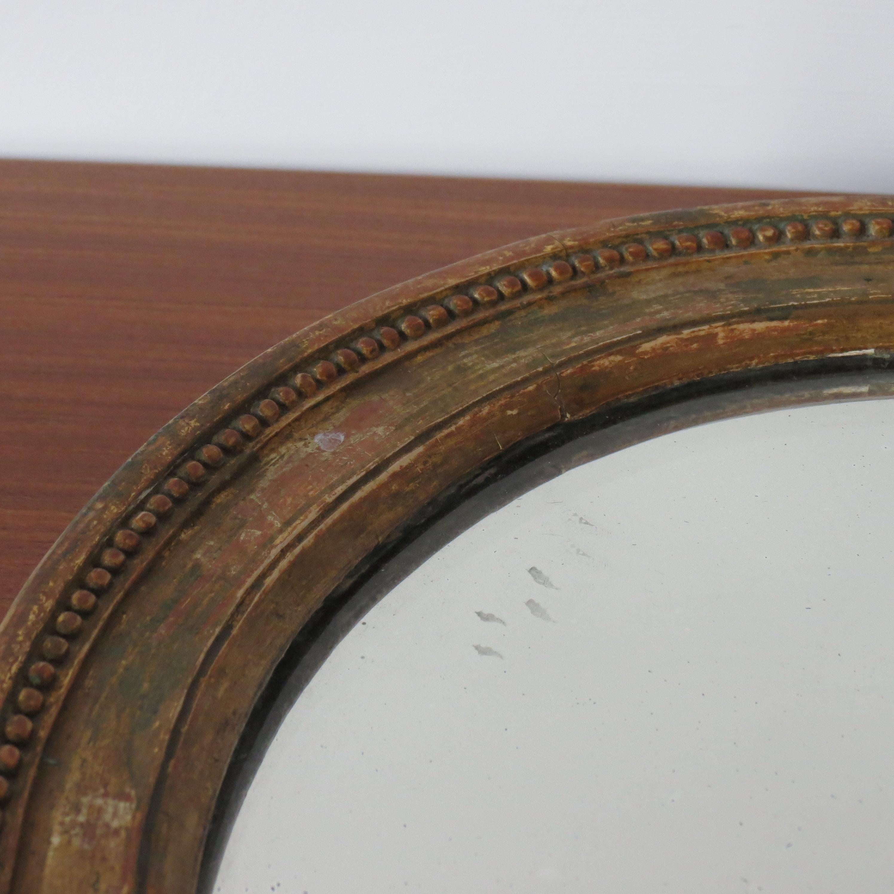 Wonderful gilt oval wall mirror, this mirror dates from the late Georgian period, circa 1830. Gilt edge decorative frame surrounds a glass mirror plate. All in original condition, distressing to the frame all over, nice original old plate with