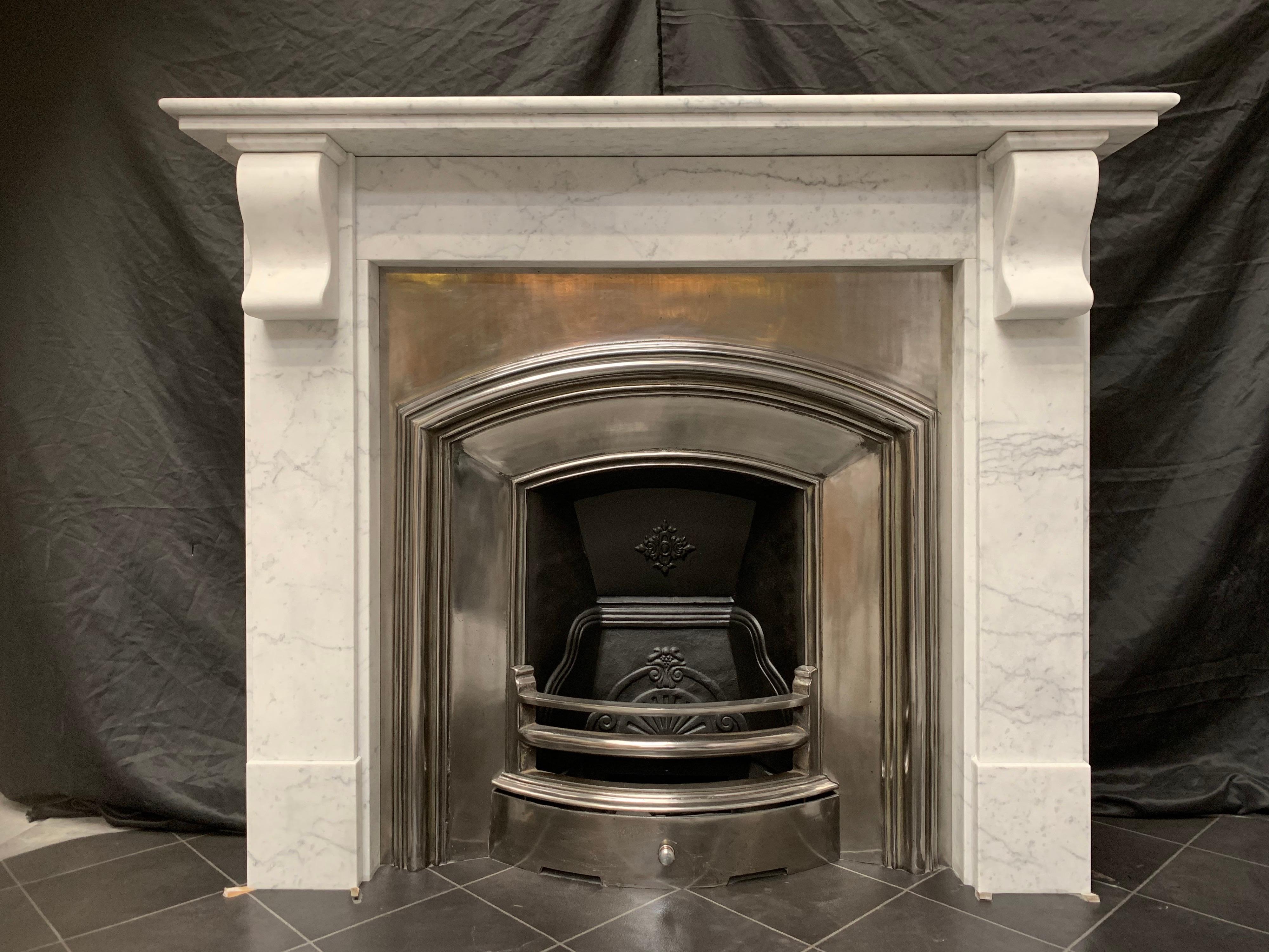 A medium sized 19th century late Victorian lightly veined Arabescato marble corbel fireplace surround. A rounded shelf with a secondary shelf supporting, sits above an unadorned frieze, flanked by a pair of geometric corbels supported in turn by