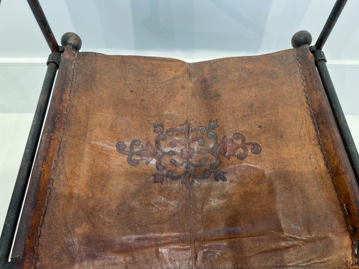 Fai un salto indietro nel tempo con questa splendida sedia Savonarola in pelle del XIX secolo con ferro da stiro. 
La sedia è caratterizzata da una seduta e uno schienale in pelle invecchiata, per offrire comfort e un tocco di eleganza vintage. La