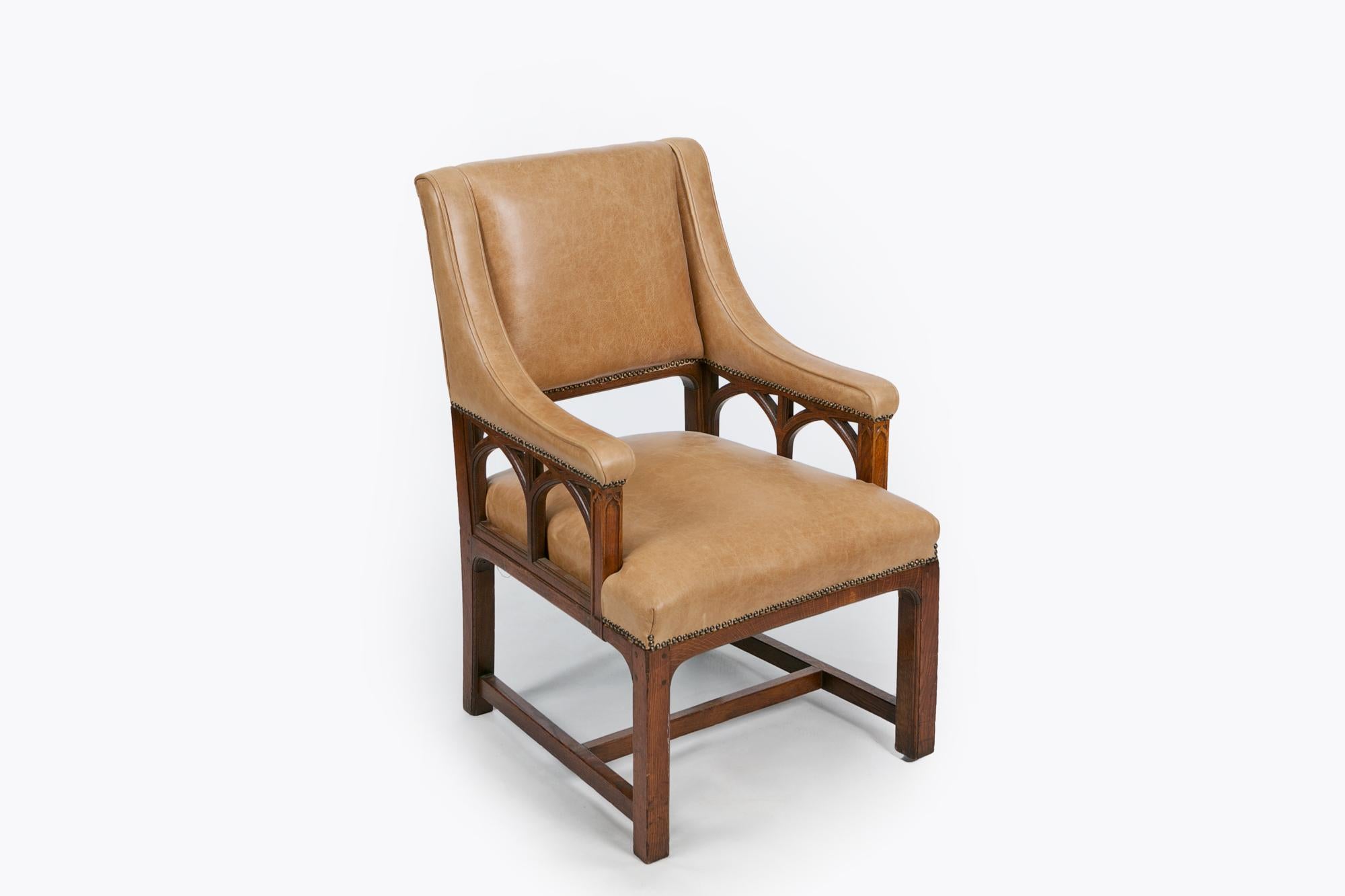 Fauteuil de bibliothèque en chêne du XIXe siècle de style gothique. Le dossier rectangulaire rembourré avec des supports en arc gothique ouvert rembourré balayé vers le bas sur le siège rembourré soulevé sur des jambes carrées jointes avec un