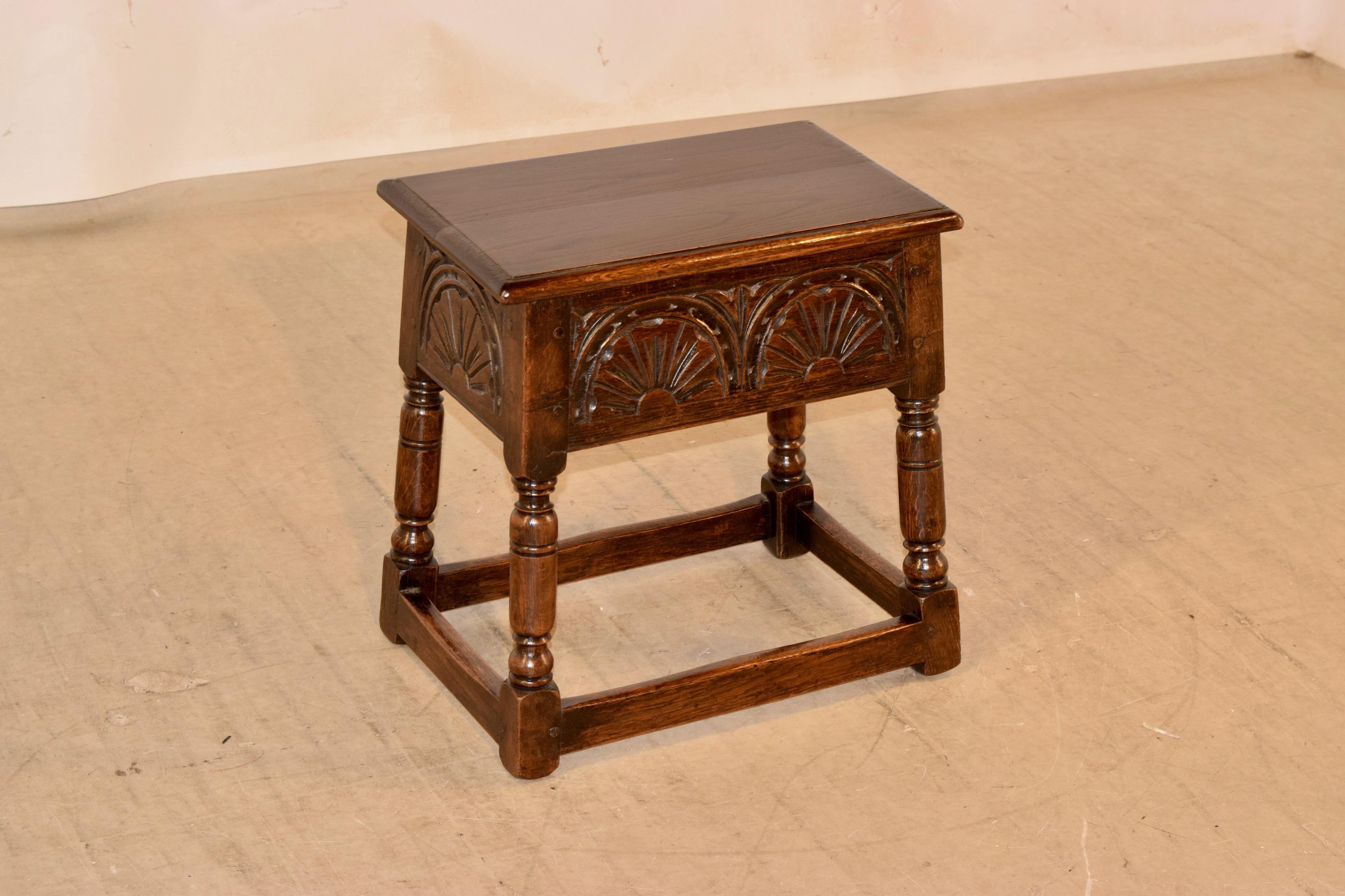 Late 19th century oak stool from England with a lift-top and lovely hand carved panels on three sides and pegged construction. Supported on hand turned splayed legs, joined by simple stretchers.