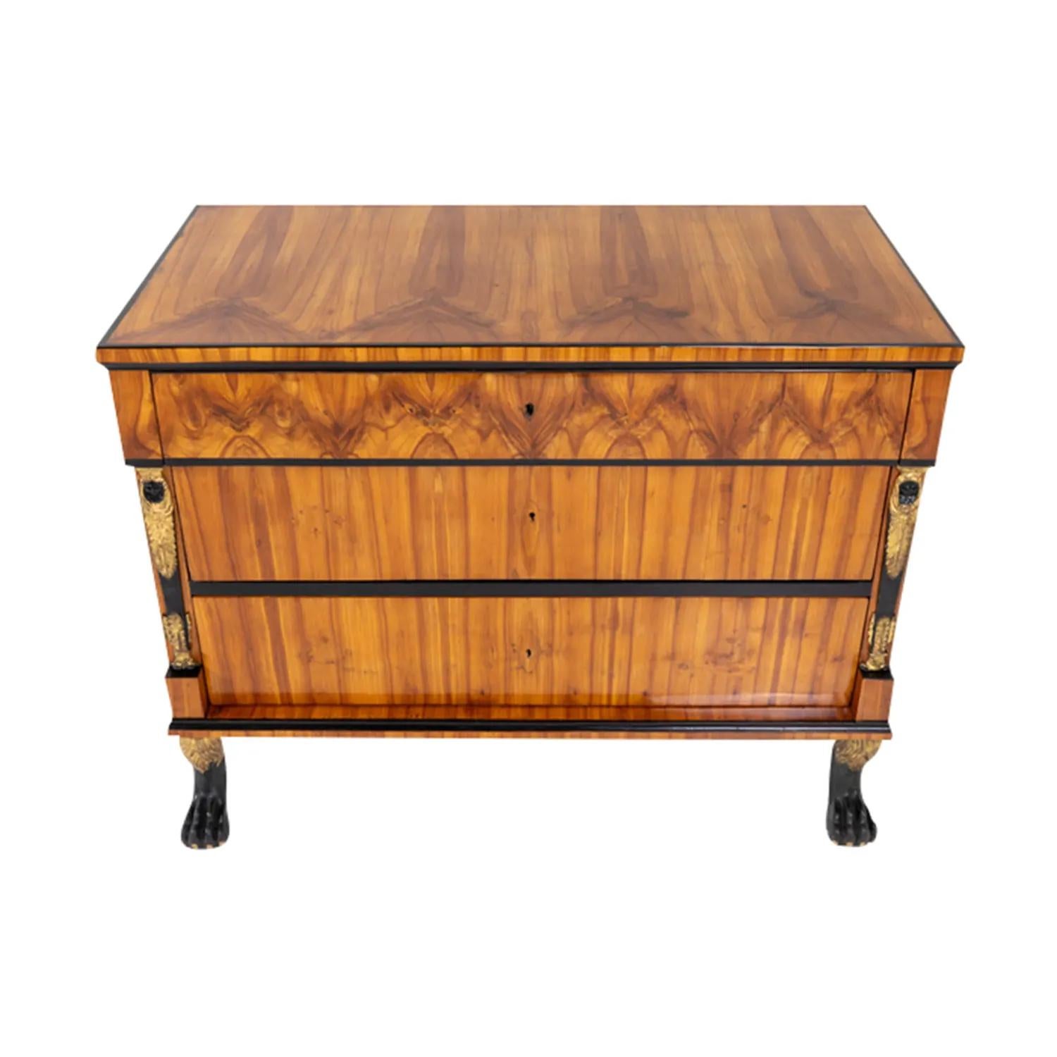 A 19th century, light-brown antique German Biedermeier chest, commode made of handcrafted Cherrywood, shellac polished and partly veneered in good condition. The cupboard is composed with two large and one small drawer, consisting its original