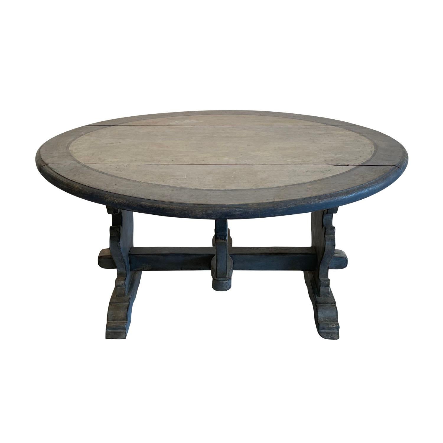 A light-grey, antique Italian oval folding table made of hand carved Pinewood with support in the Trestle design, in good condition. The two sides of the dining table are foldable. The very thick table top has a wide painted border along the rim.