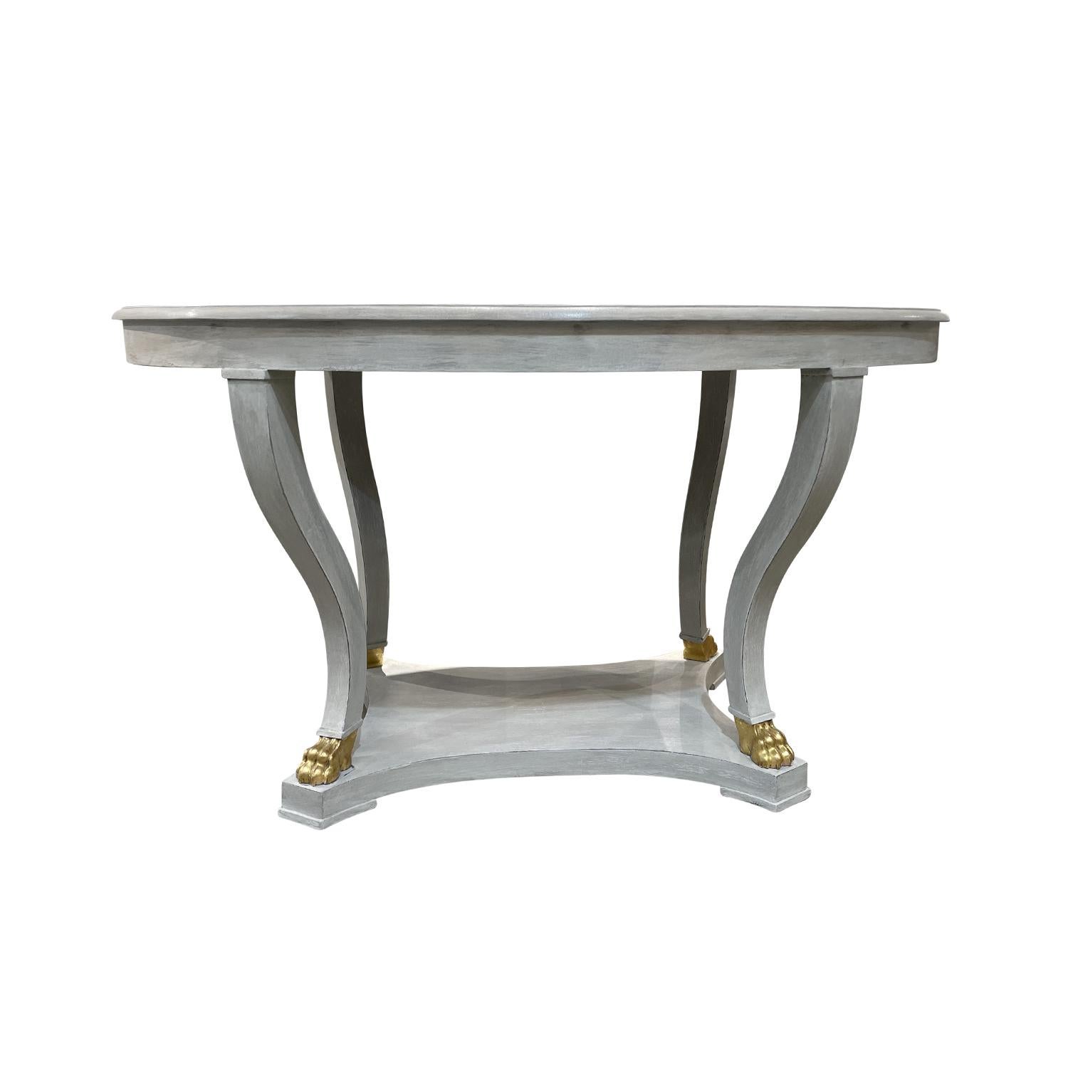 An antique 19th century Swedish Gustavian oval wooden dining table, in good condition. The Scandinavian painted Pinewood center table has a grey waxed patina. The four legs are accentuated with gilded hand carved lion paws. Wear consistent with age