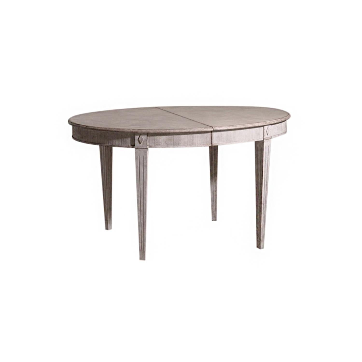 A light-grey, antique Swedish Gustavian extendable dining table made of hand carved Pinewood with two leaves and apron, enhanced by wood carvings. The Scandinavian half round table is standing on four straight square tapered fluted legs, detailed in