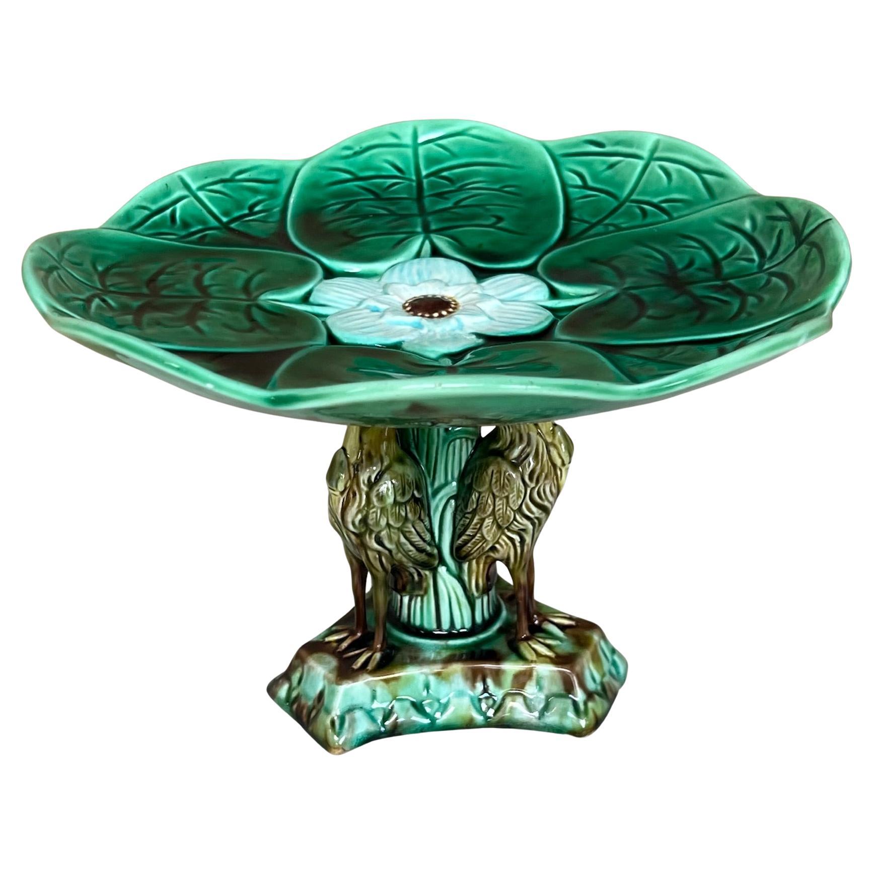 Centre de table antique en majolique. Le piédestal est composé de trois grues appuyées sur des branches qui soutiennent des feuilles de nénuphar et une fleur centrale. Le support est attribué à Adams & Bromley, qui ne marquaient généralement pas