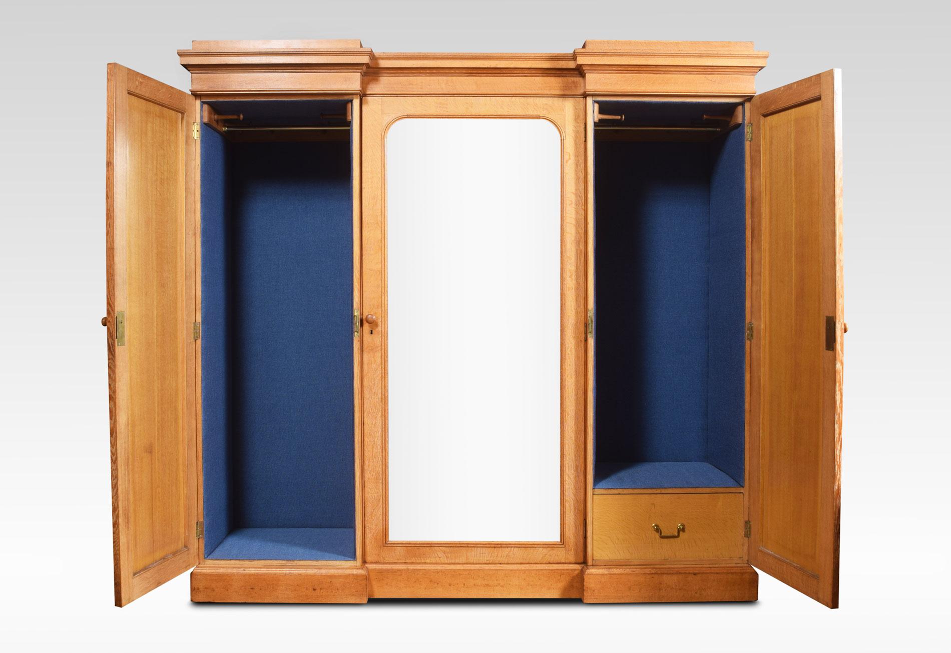Large and impressive 19th century limed oak triple wardrobe compactum. The flared cornice above a large mirrored door opening to reveal compartment complete with linen slides over a chest of drawers fitted with brass handles. Flanked by two large