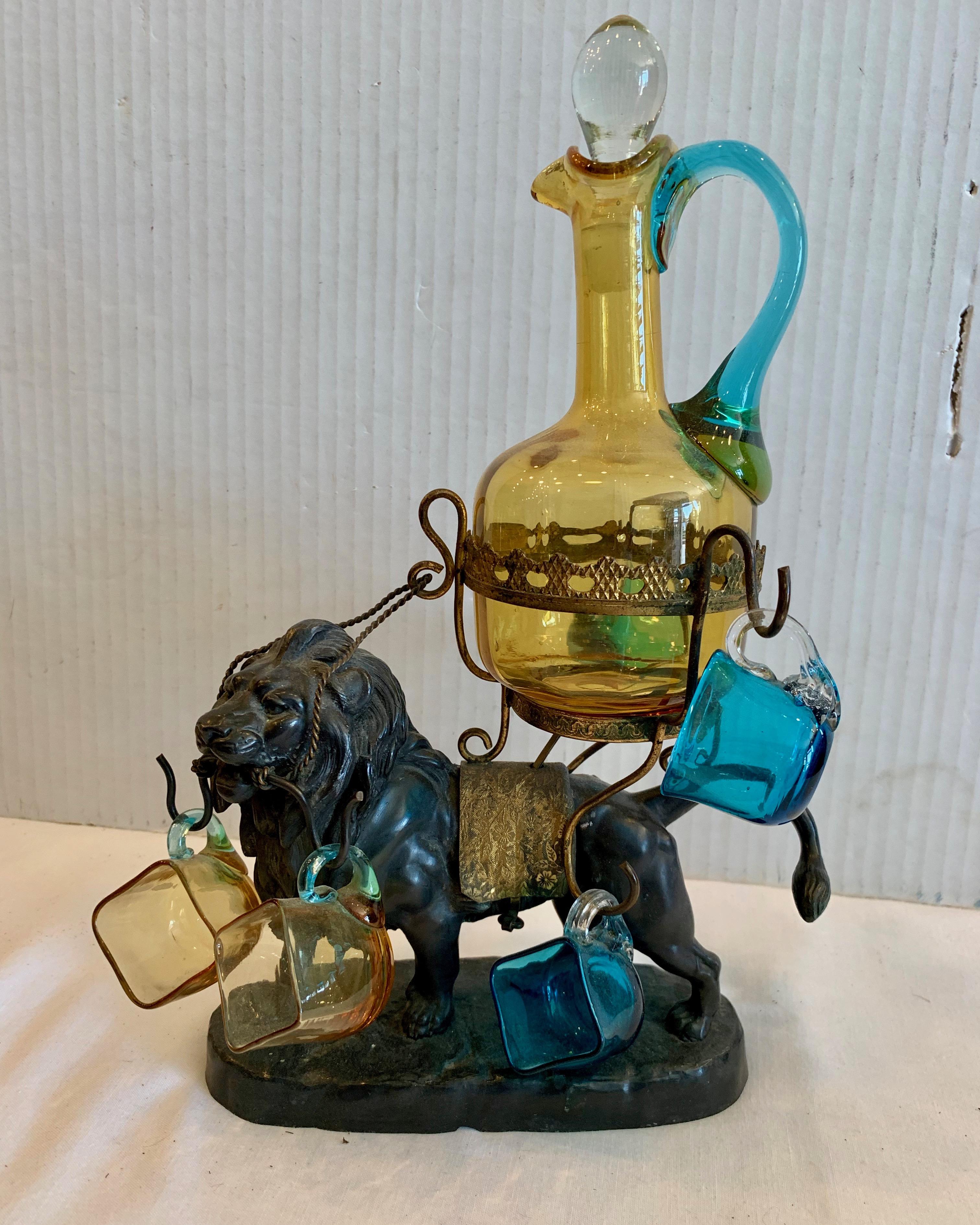 A finely cast bronze figure of a lion holding the original decanter and 6 glasses for sipping. An unusual antique barware accessory