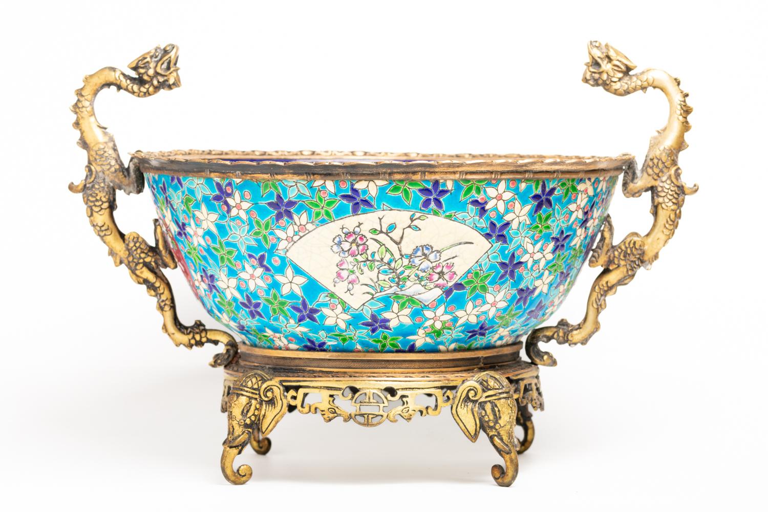 This magnificent late 19th century Longwy French jardinière features a beautiful cloisonné enamel body- mounted in bronze. The rich blue enameled exterior of the jardinière is decorated with a variety of floral and tree forms, including two central