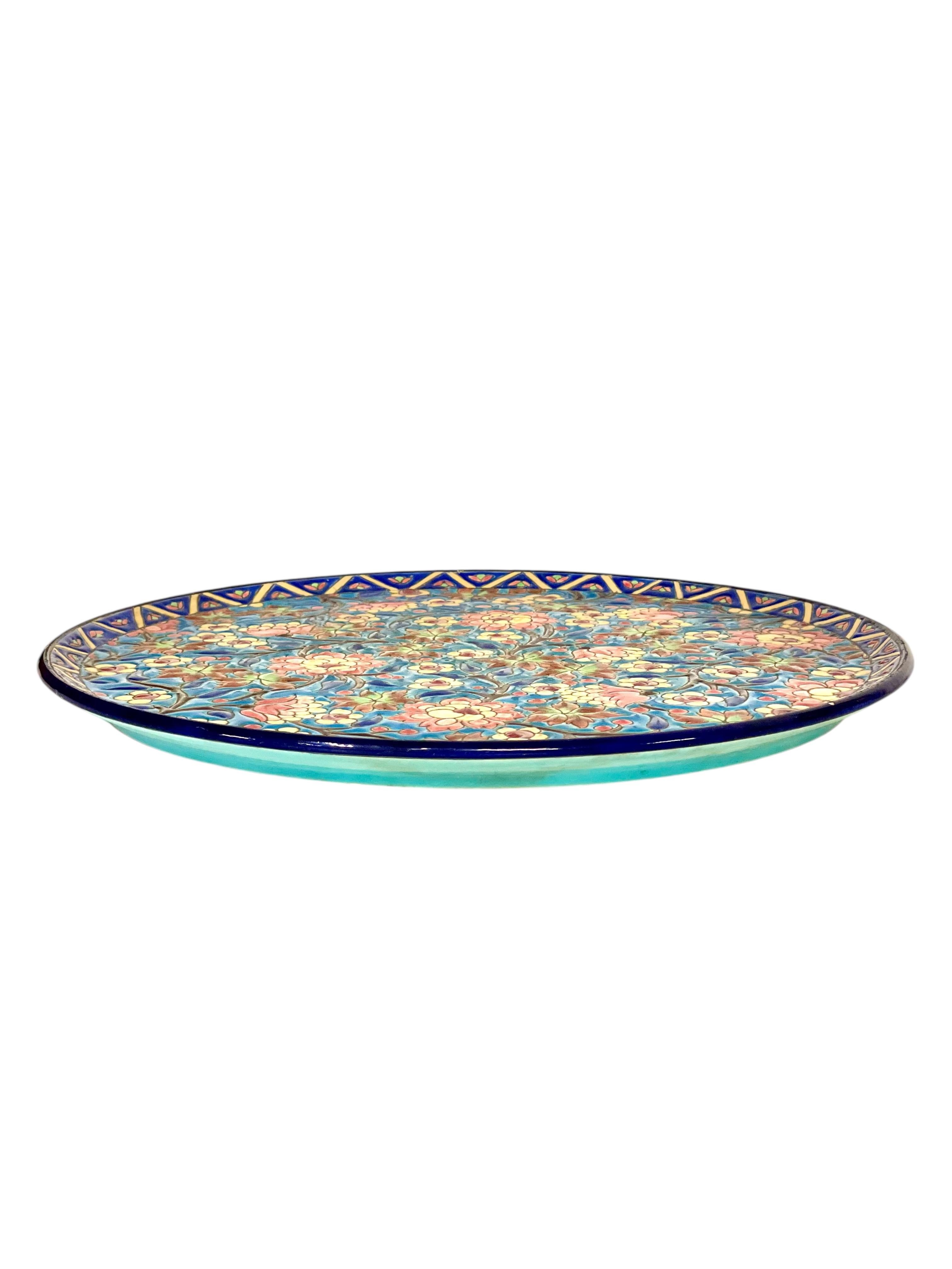Este exquisito siglo XIX,  El plato de cerámica es una asombrosa creación de la renombrada manufactura Longwy, célebre por su maestría en la cerámica decorativa. El plato presenta un cautivador motivo floral con delicadas flores en tonos rosa,