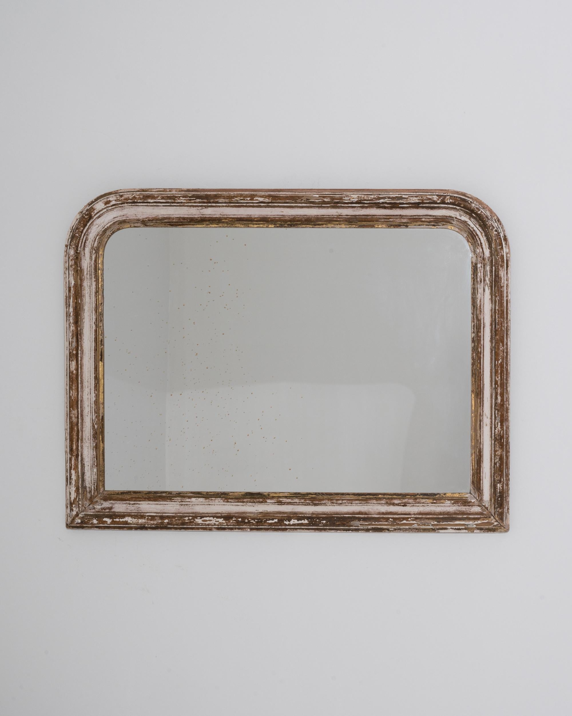 A wooden mirror made in 19th century France. This vintage mirror offers a relaxing and rustic charm to decorate the home, featuring an eye-pleasing finish and a gently rounded frame. The off-white paint that coats the surface of the frame has worn