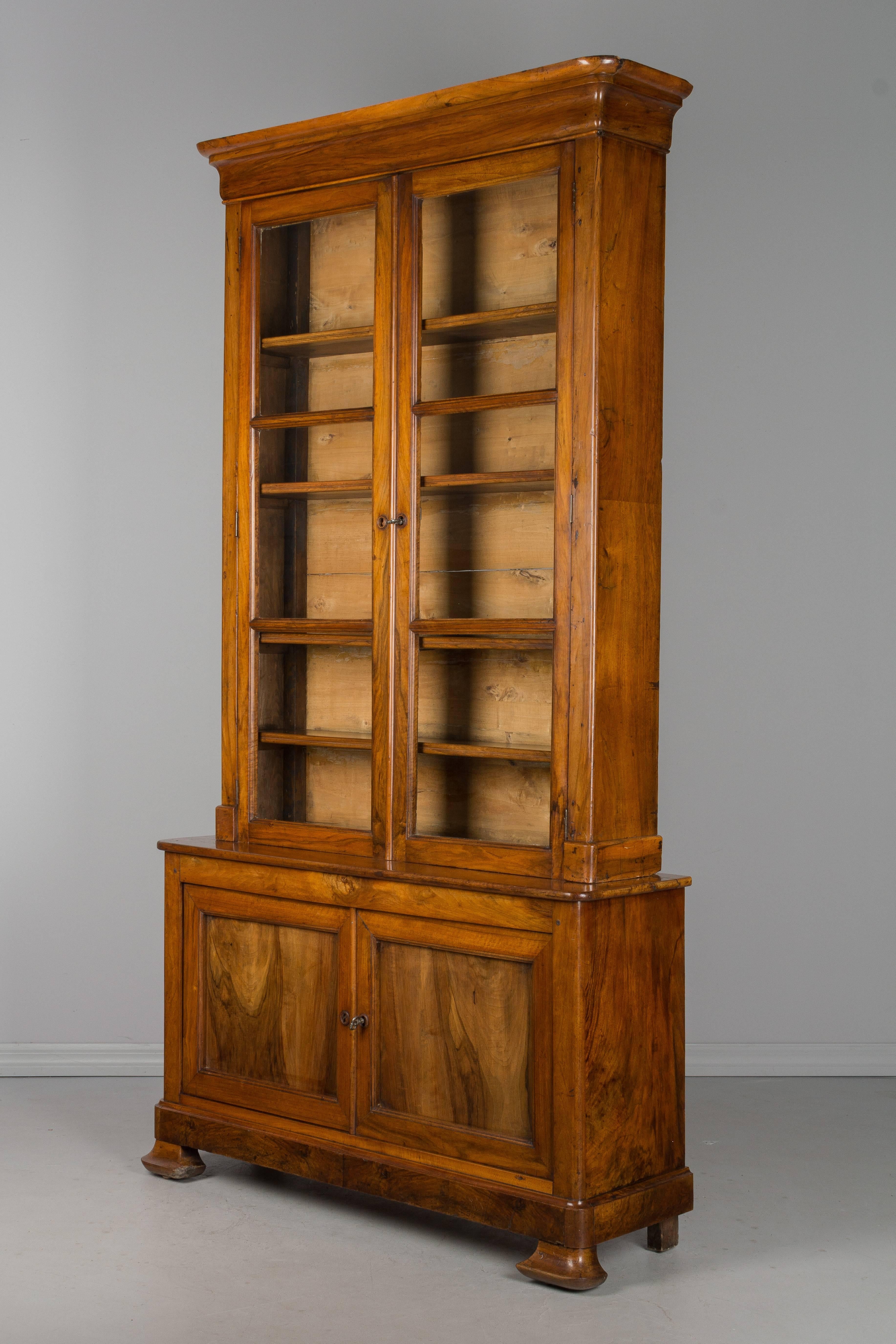 A 19th century French Louis Philippe bibliotheque made of solid walnut. The upper book case has the original paned glass doors and opens to four fixed shelves with an inside depth of 7