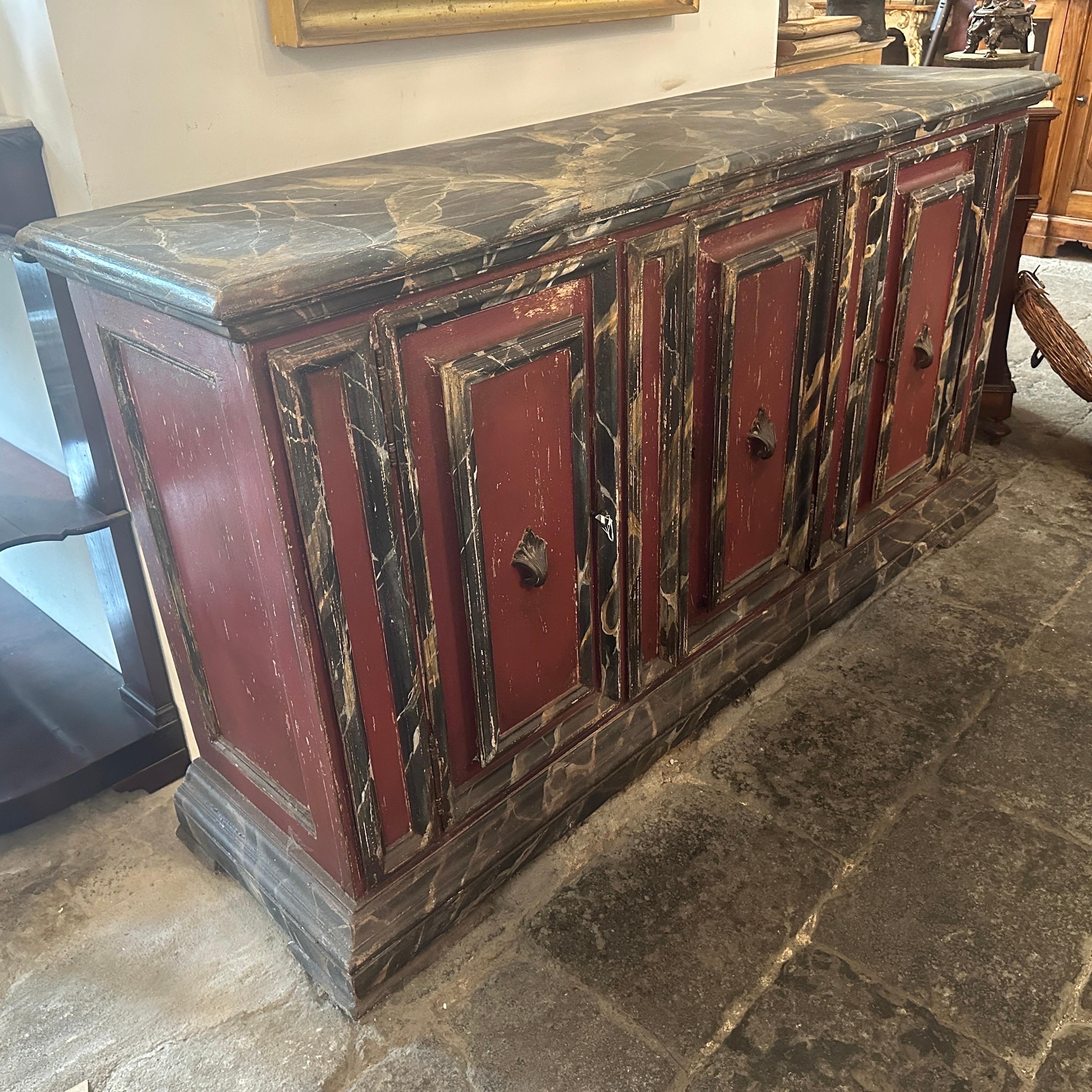A lacquered wood italian buffet in original conditions and patina. The top and the frames are lacquered as fake marble Portoro, the other parties are in an elegant burgundy red. It's a furniture with an hot personality and it can be used in classic