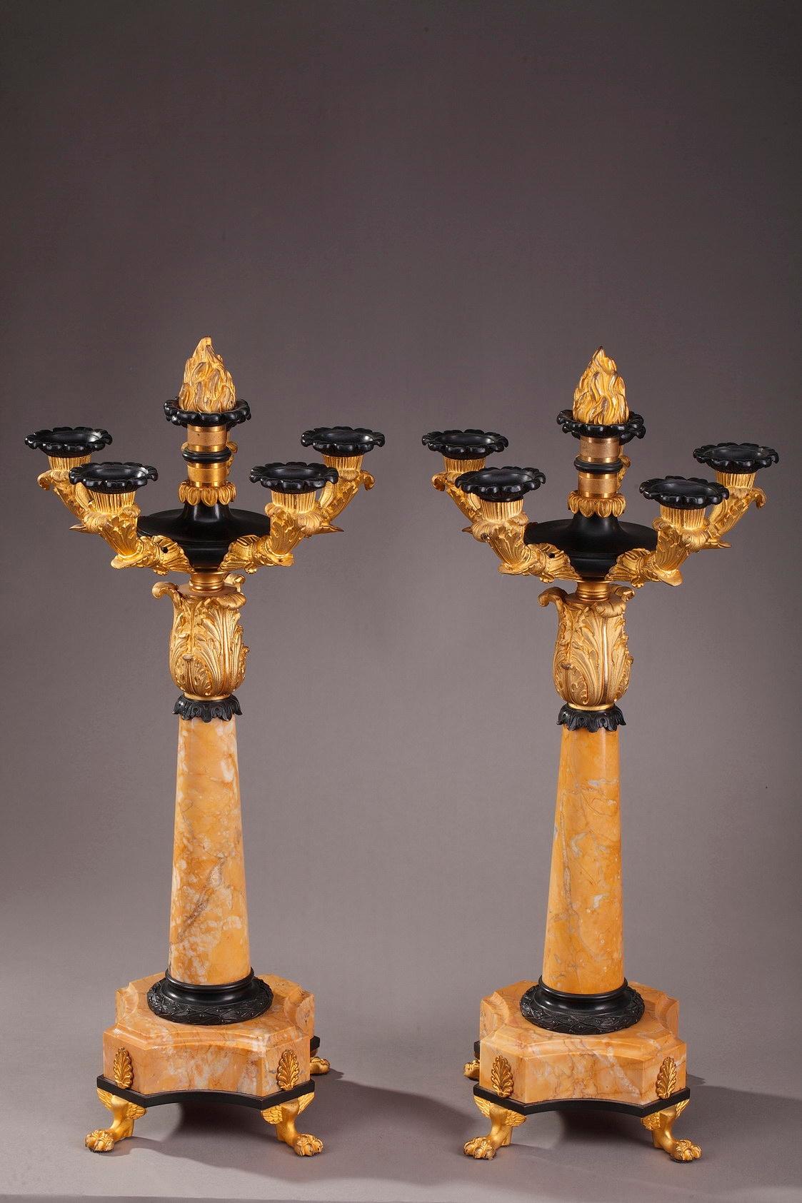 A set of table candelabras, each with five branches. The branches and feet of these large candelabra are in gilt and patinated bronze. They are richly decorated with acanthus leaves and foliage. The base and central shaft are in Sienna marble. Each