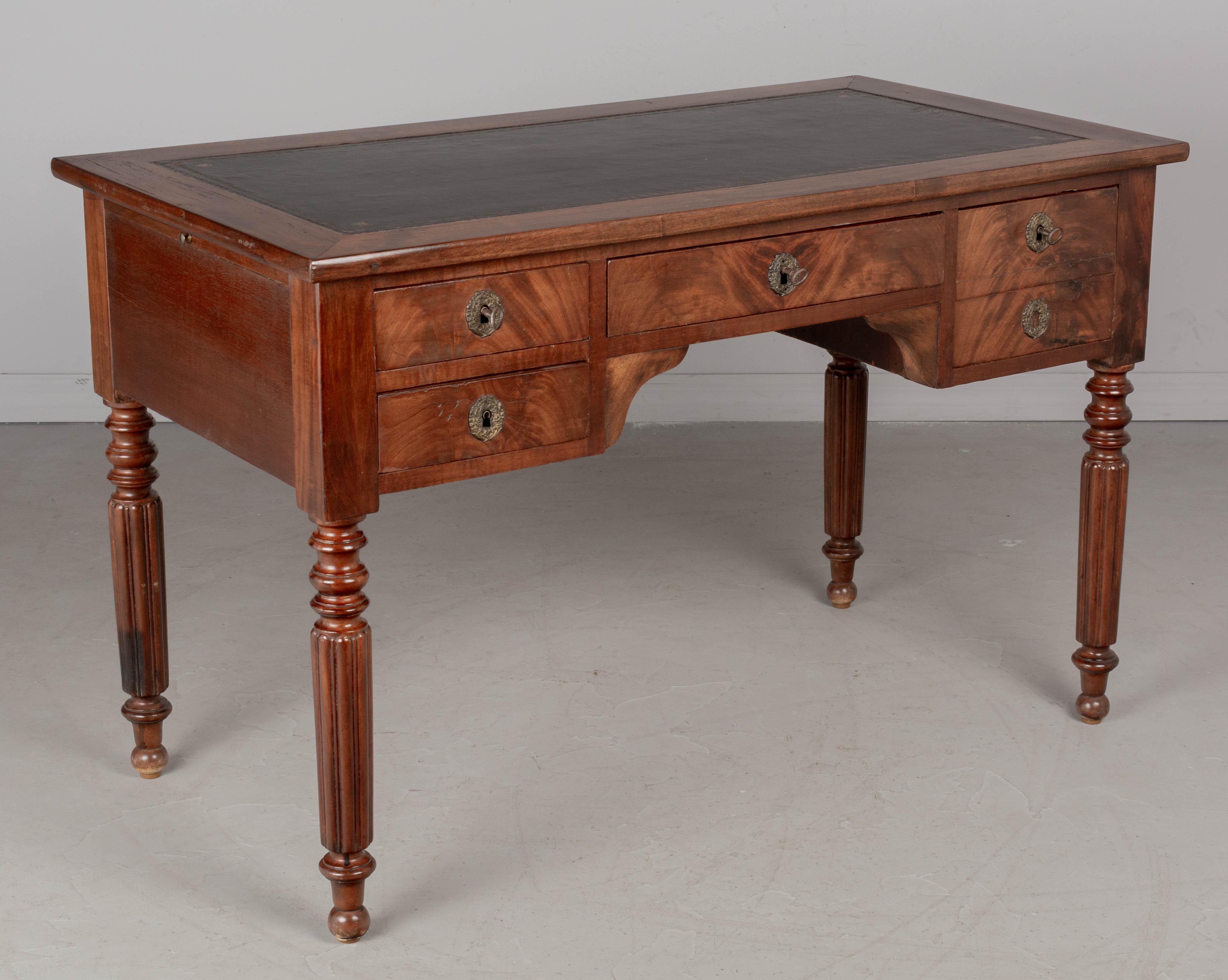 A French Louis Philippe style bureau plat, or desk made of solid and veneer of mahogany. Double sided, the back has false drawers so this desk may be free floated in a room. Four dovetailed drawers with brass escutcheons, working locks and three