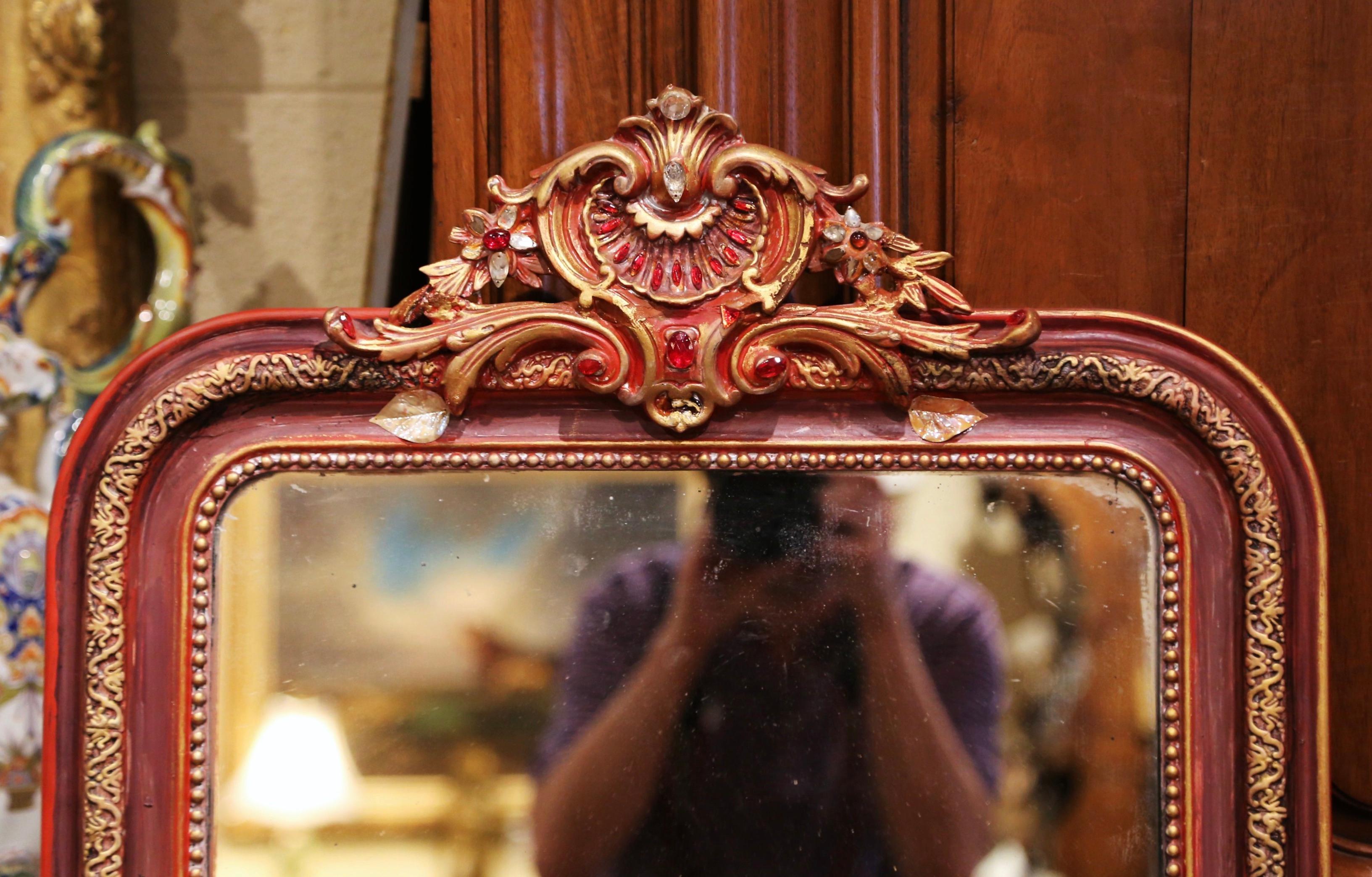 This elegant, antique wall mirror was crafted in France, circa 1880. The mirror is decorated at the pediment with a large cartouche shell in the center flanked with carved floral and leaf motifs and embellished with faux jewel accents. The two-tone