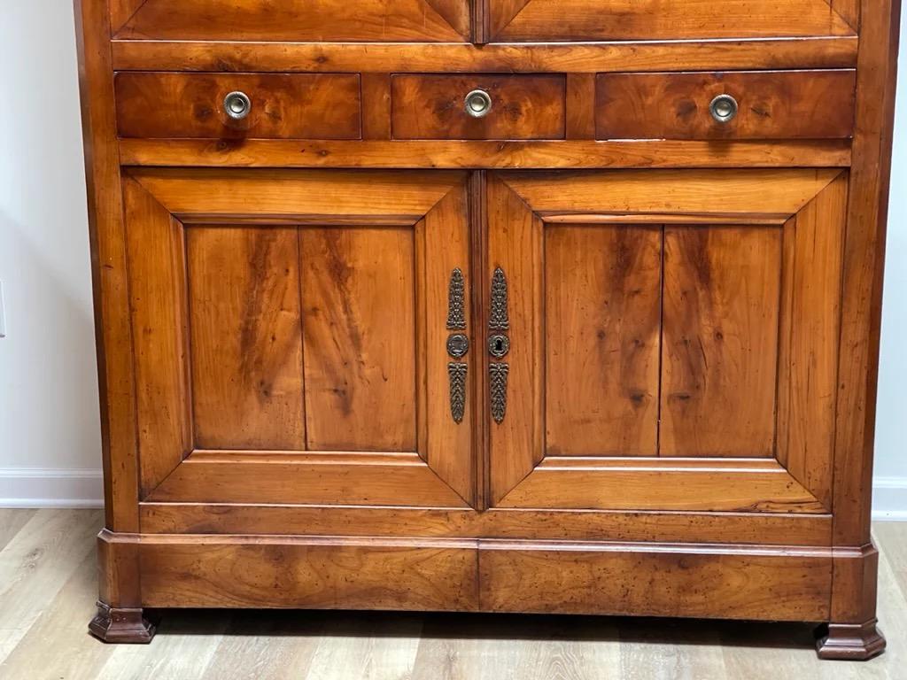 Gorgeous 19th C. Louis Philippe cherry wood Armoire, top has two panel pocket doors over three small drawers, base has two panel cupboard doors, C. 1850. Has been tastefully adjusted to fit a television on the interior.
  
