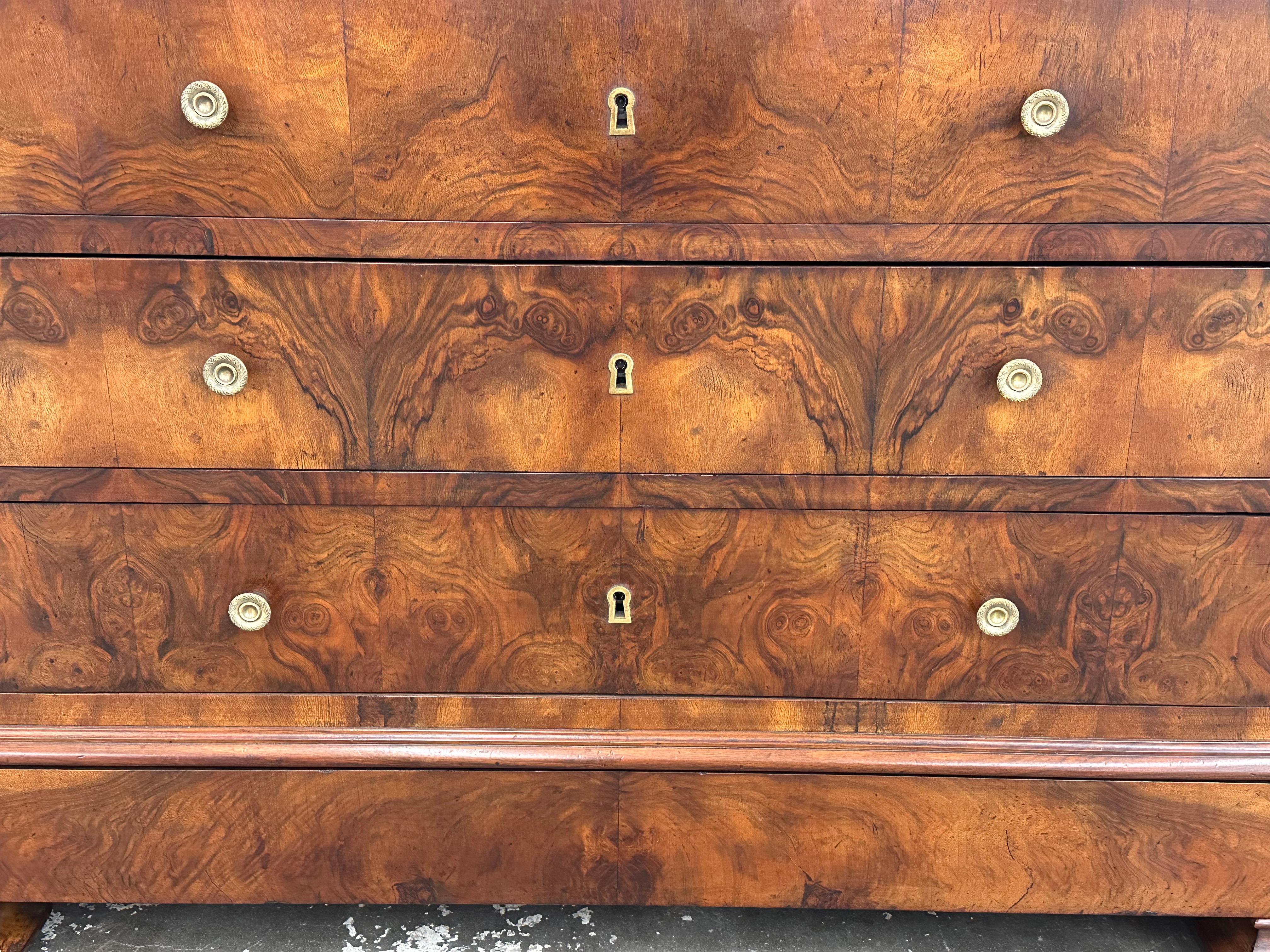 This is a beautiful 19th century Louis Philip chest of drawers! The burled wood has exquisite design and is such a feast for the eye! Simple brass knobs and keyholes add the perfect accent, and the gorgeous black and grey swirled marble slab on top