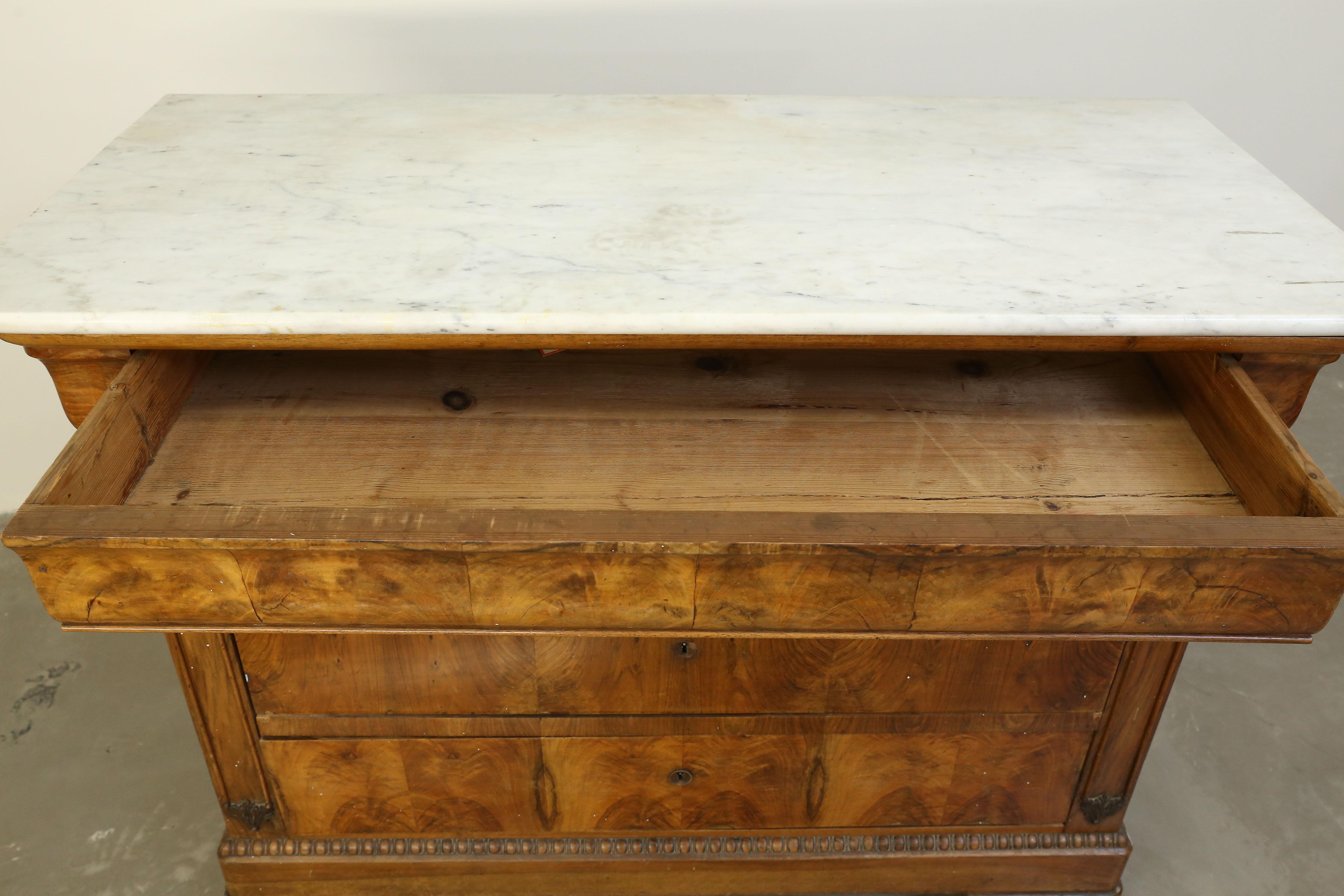 Antique 19th century French Louis Philippe chest of drawers featuring burled walnut and Carrara marble top. This chest has a hidden drawer at the top and 3 drawers of equal size below.